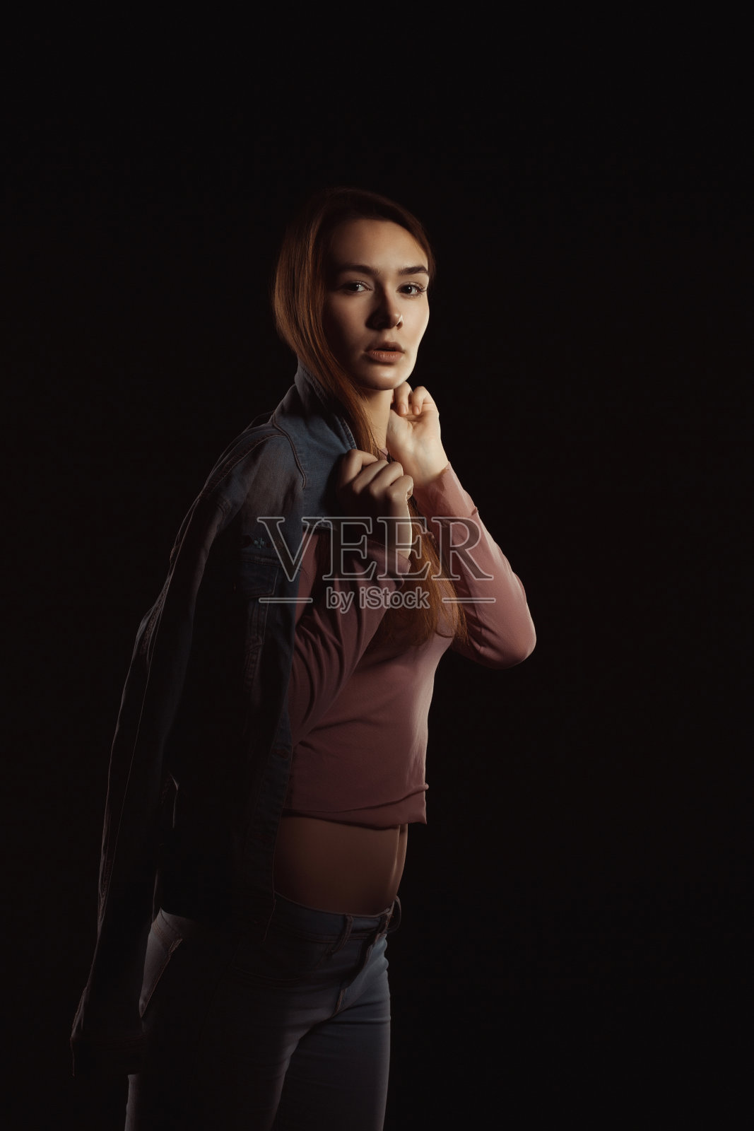 漂亮的黑发女人，自然的妆容和完美的皮肤，穿着时髦的牛仔裤夹克照片摄影图片