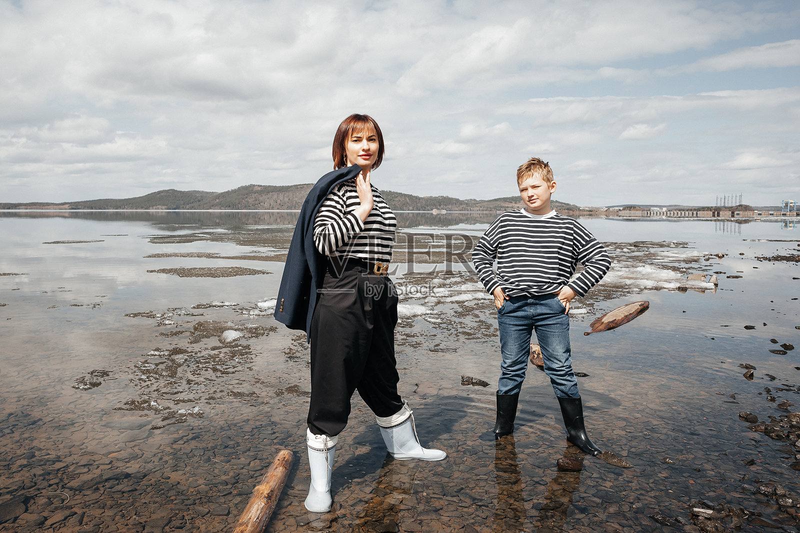 快乐的母子站在河边，都穿着条纹背心。照片摄影图片