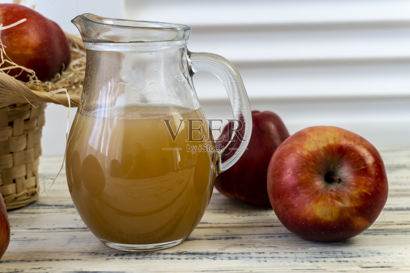 篮子里的红苹果，木桌上的罐子里的苹果汁照片摄影图片