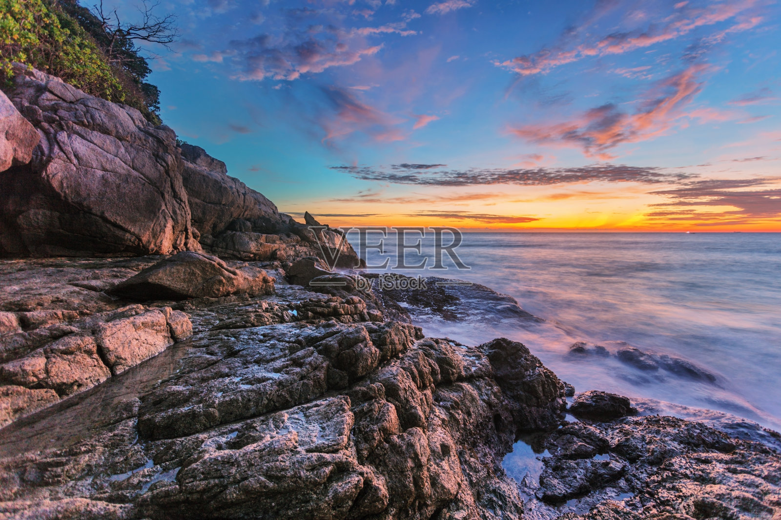 岩石海滩上美丽的日落。照片摄影图片