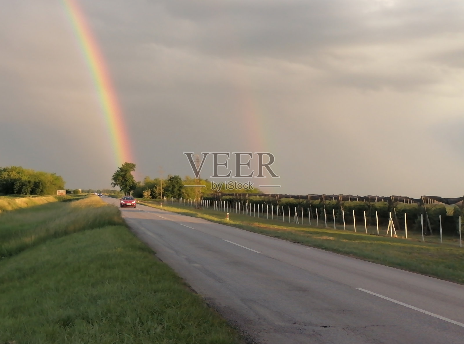 在柏油路与汽车和彩虹上面的观点照片摄影图片