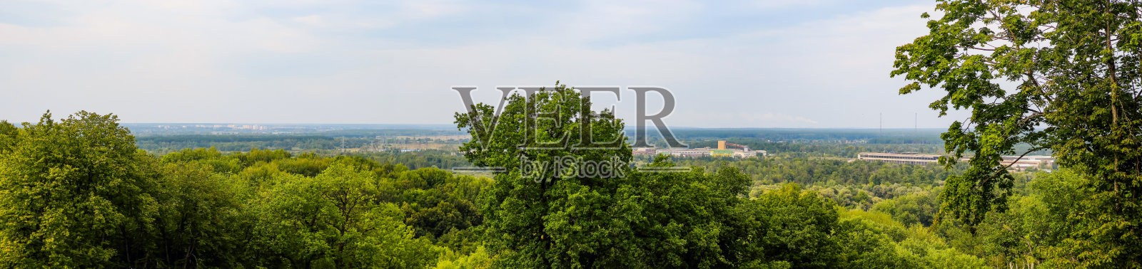 从上面可以看到绿树和城市边缘的全景。照片摄影图片