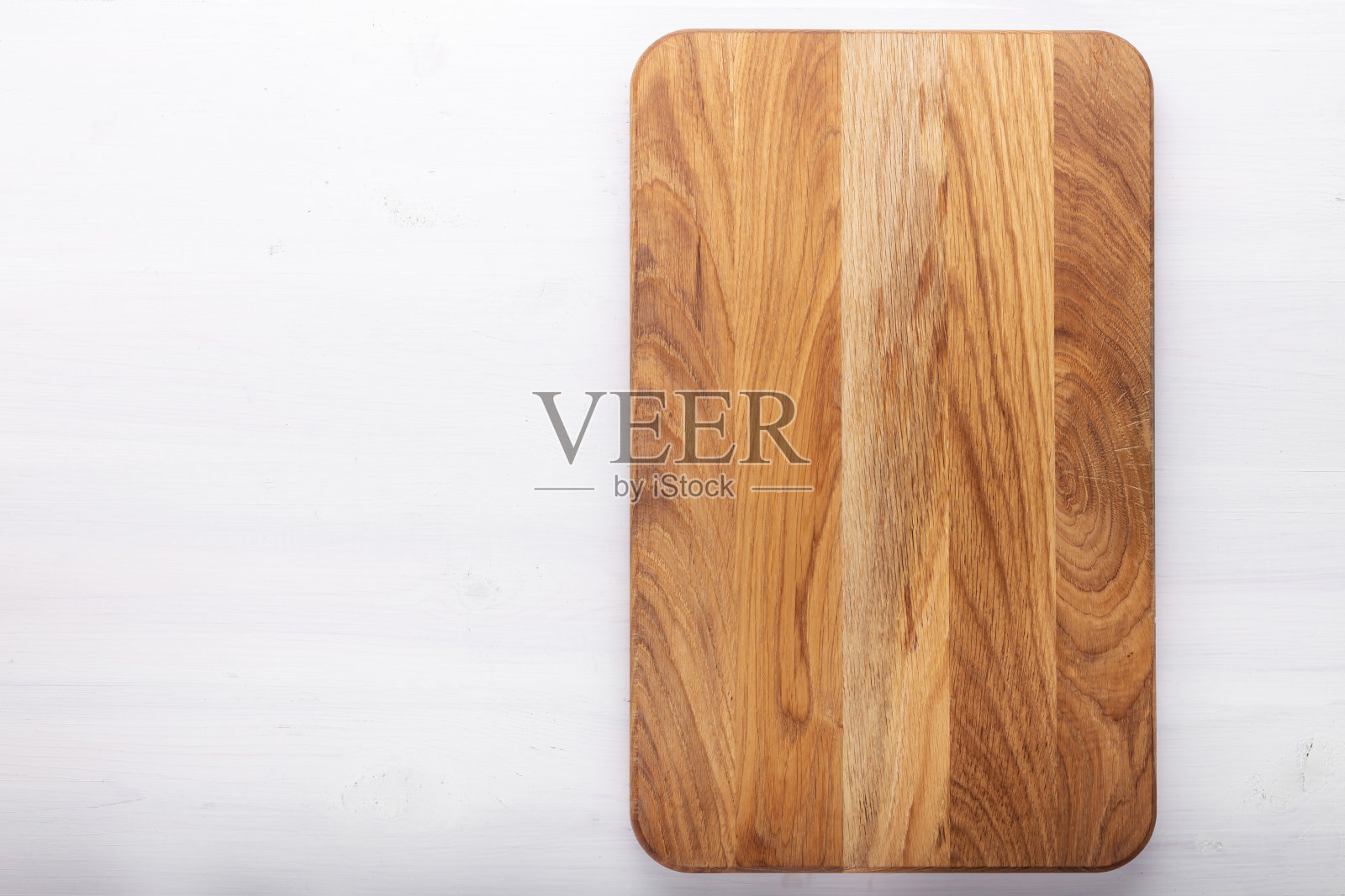 长方形的砧板放在白色的木桌上。准备食物的工具和厨房用具。照片摄影图片