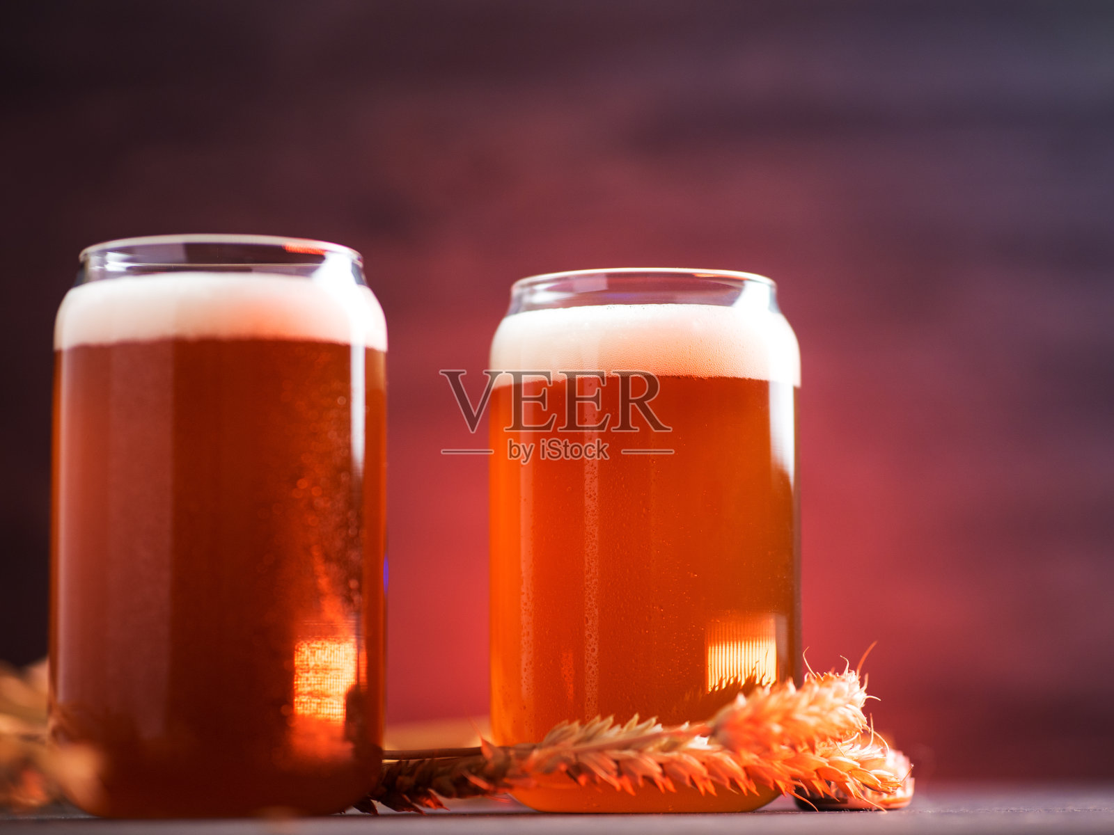 特写两杯未经过滤的精酿啤酒在一个黑色的桌子上有小麦穗照片摄影图片