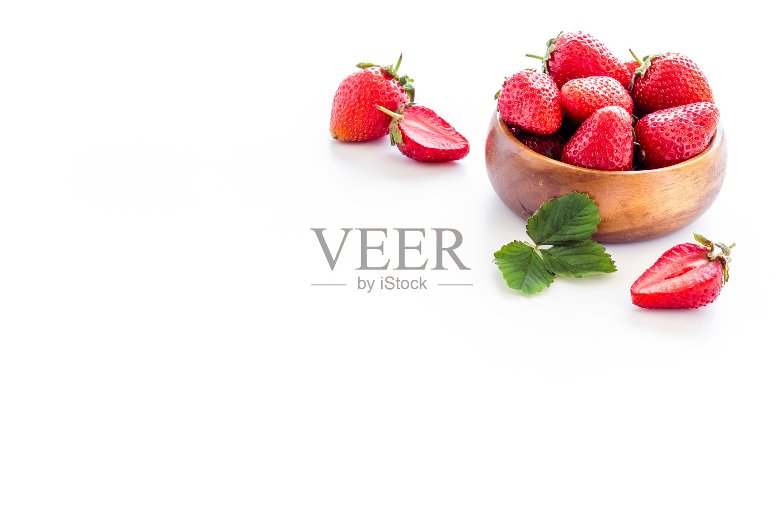 草莓放在带叶子的木碗里，靠近照片摄影图片