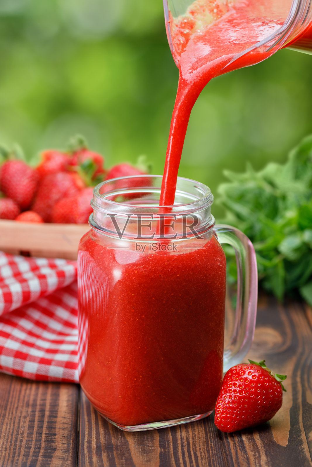 草莓汁从罐子倒入玻璃杯照片摄影图片