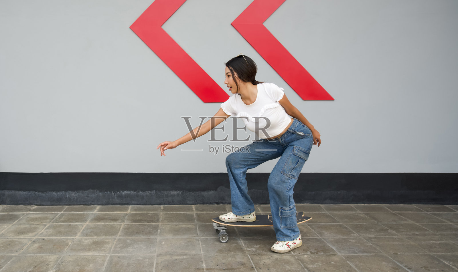 在人行道上玩滑板、头戴太阳镜的年轻亚洲女性照片摄影图片