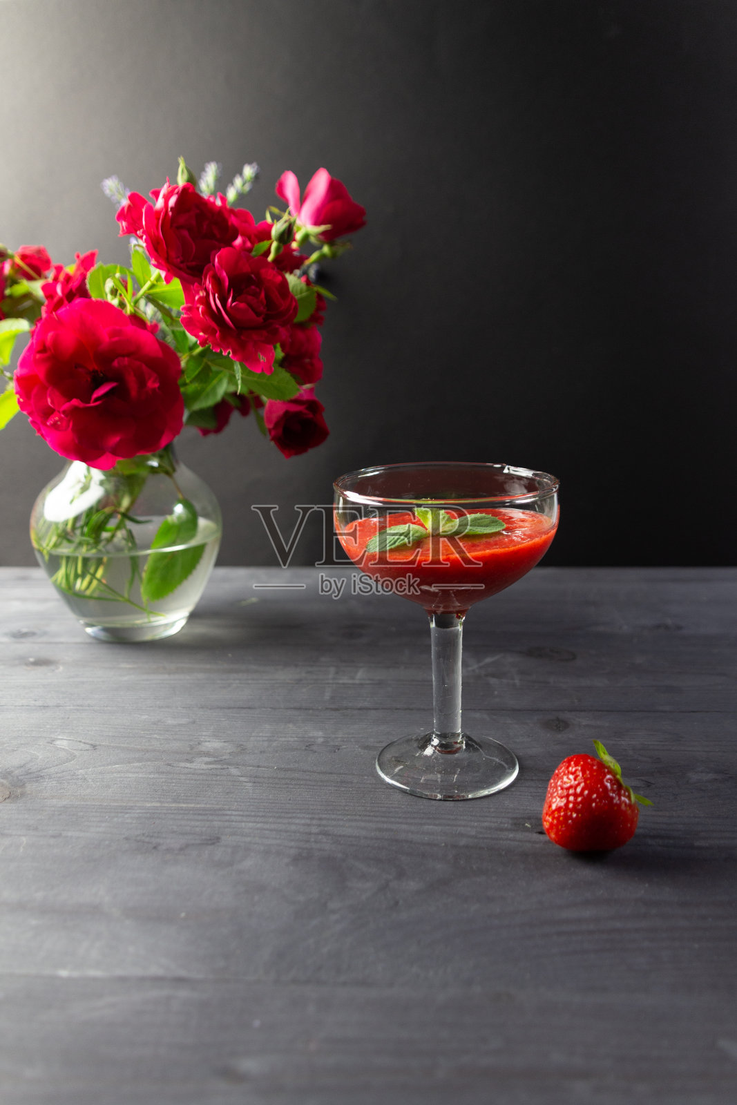 草莓泥甜点，薄荷叶玻璃碗，玫瑰花瓶在木桌上照片摄影图片