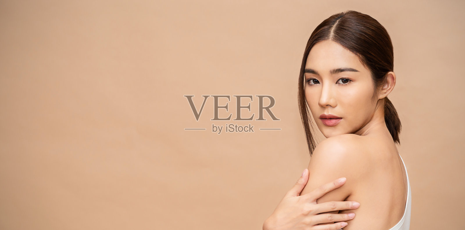 肖像的美丽微笑的亚洲妇女在她的打扮期间，将乳液涂在她的手臂皮肤。可爱的亚洲模特女孩。护肤身体乳，美容诊所护肤spa，女性生活方式旗帜照片摄影图片