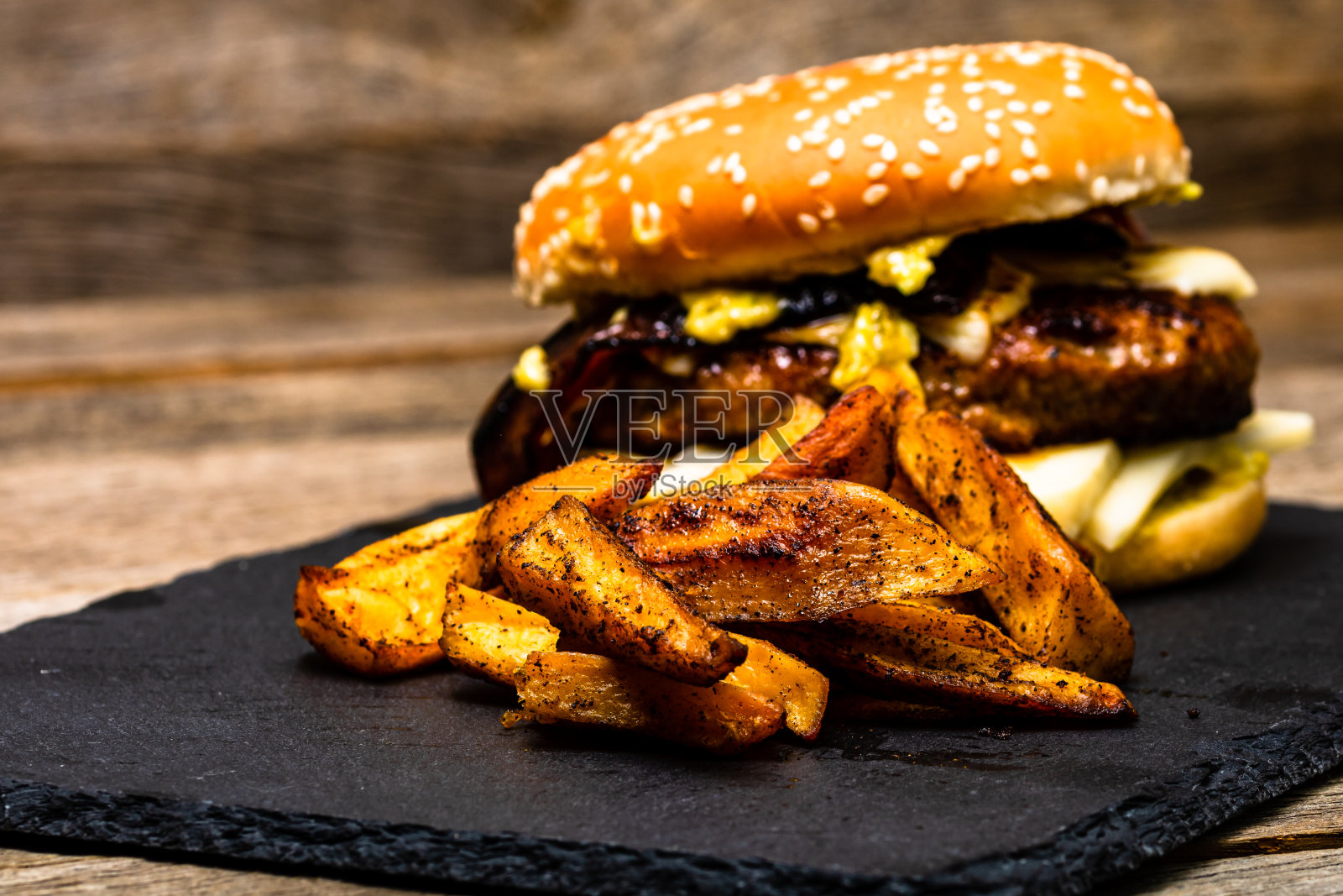 木桌上放着自制的新鲜美味的芝士汉堡和炸土豆照片摄影图片