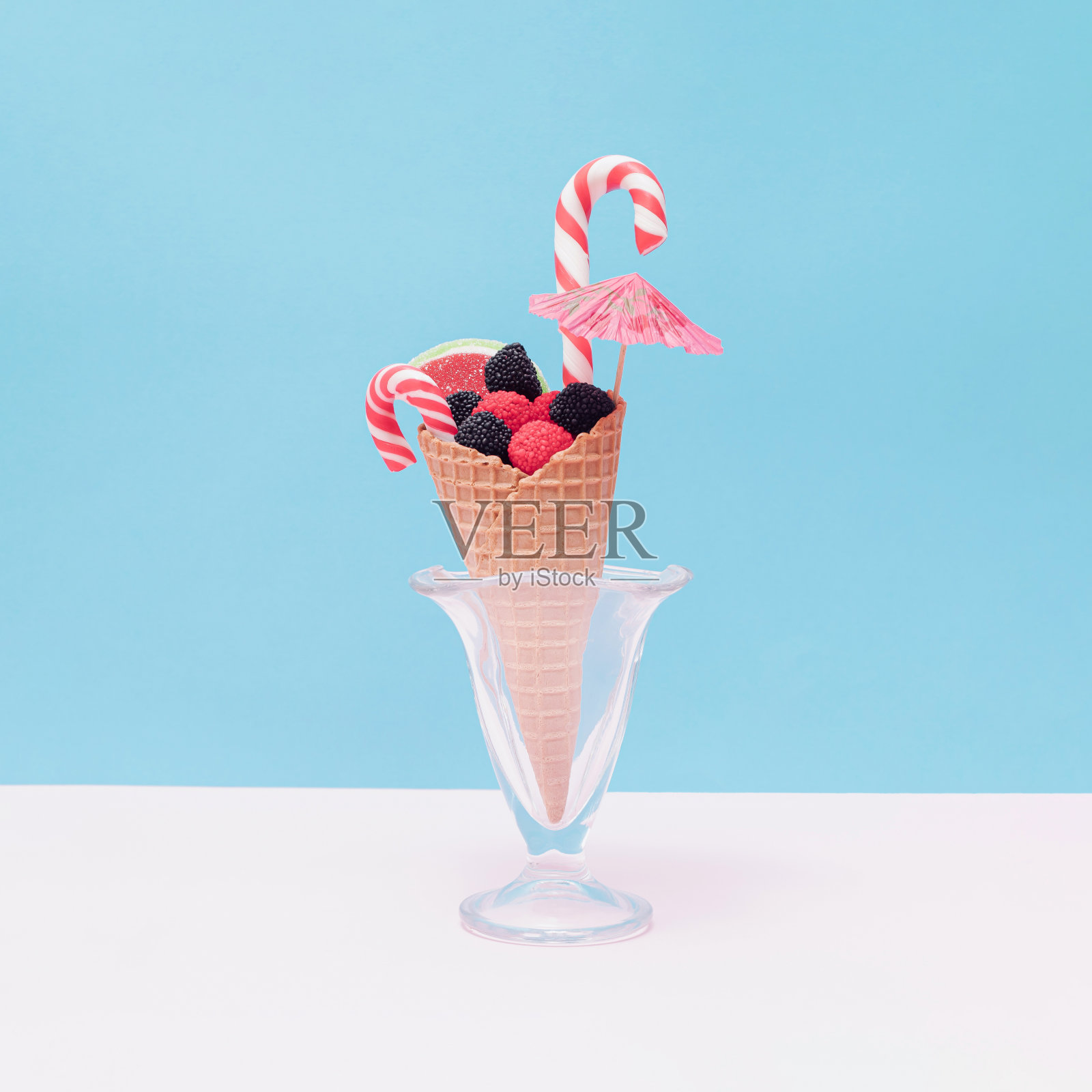 不同形状和颜色的果冻糖果在一个冰淇淋蛋筒和雨伞在一个玻璃。照片摄影图片