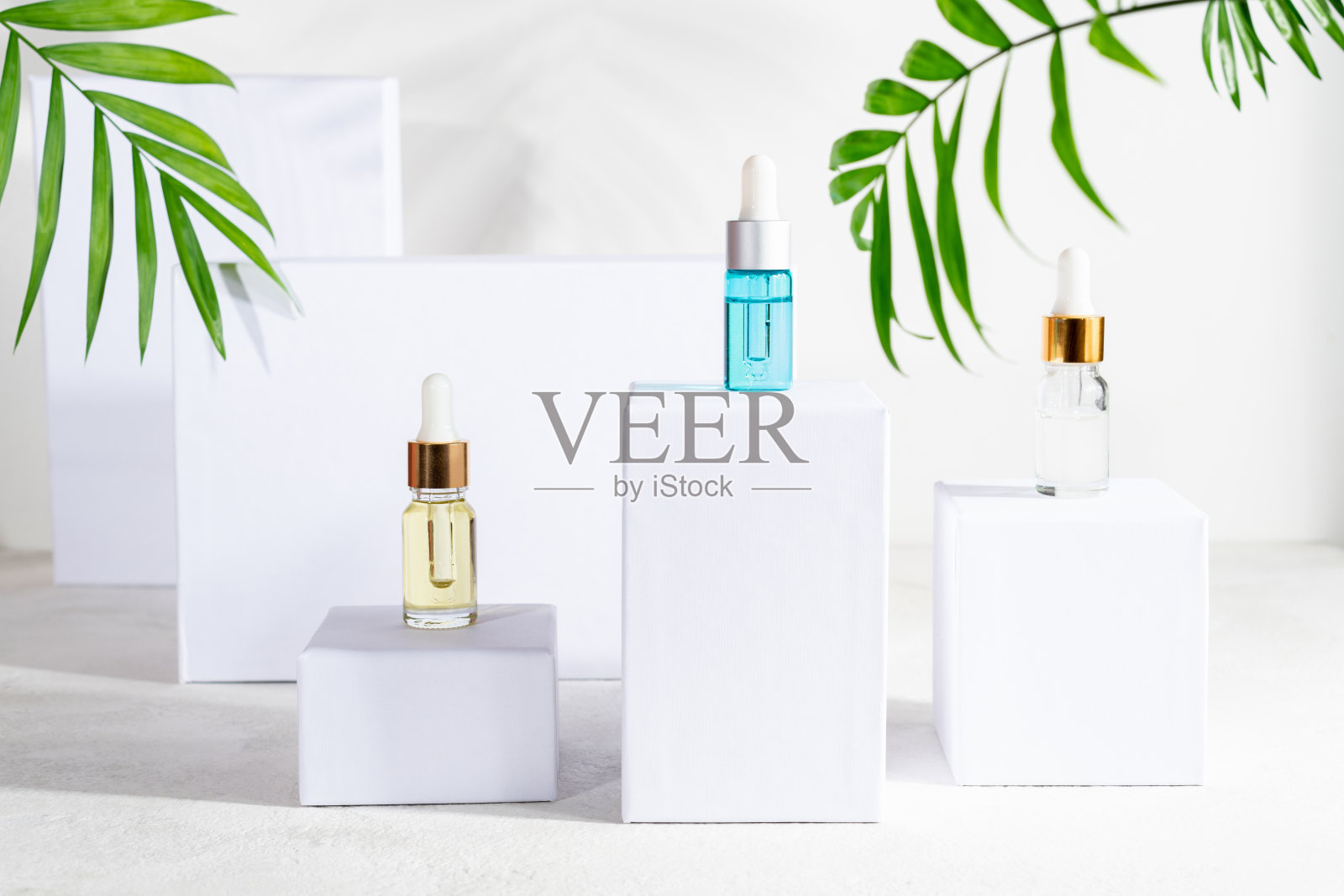 天然化妆品瓶与滴管，皮肤护理美容产品-血清，乳液，草药化妆品在白色裙与绿叶。用于女性面部皮肤白皙站立照片摄影图片