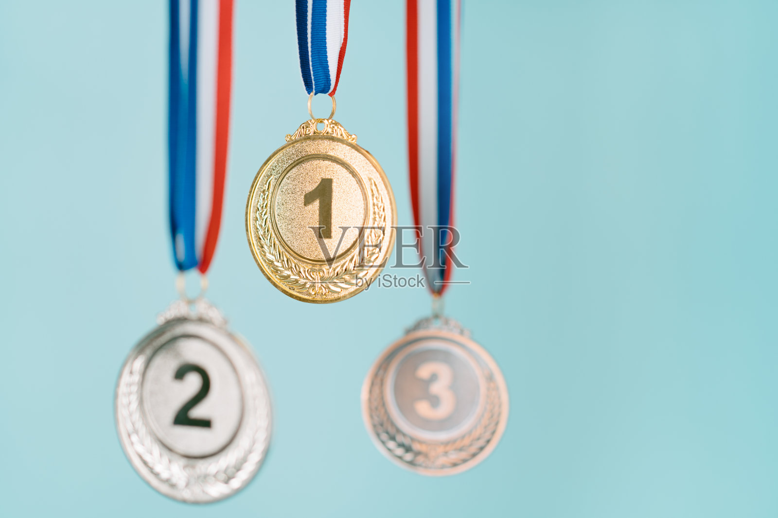 三枚奖牌(金、银、铜)，蓝色背景。奖励和胜利的概念。本空间照片摄影图片