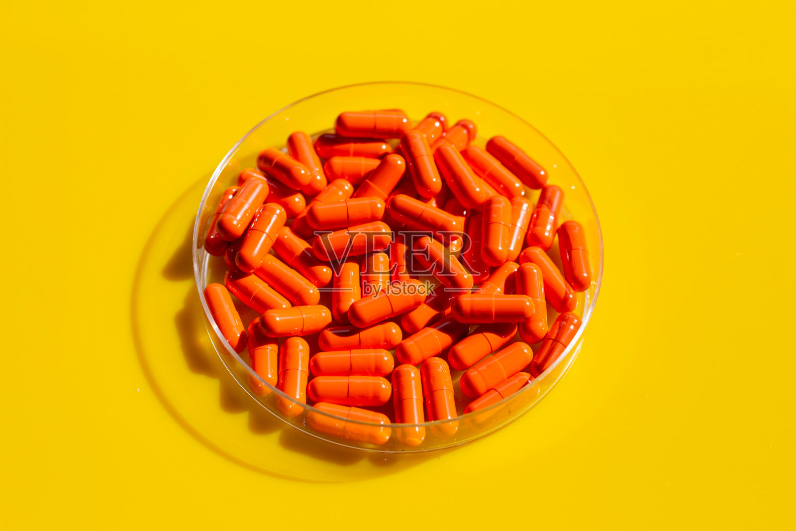 橙色胶囊，黄色背景。照片摄影图片