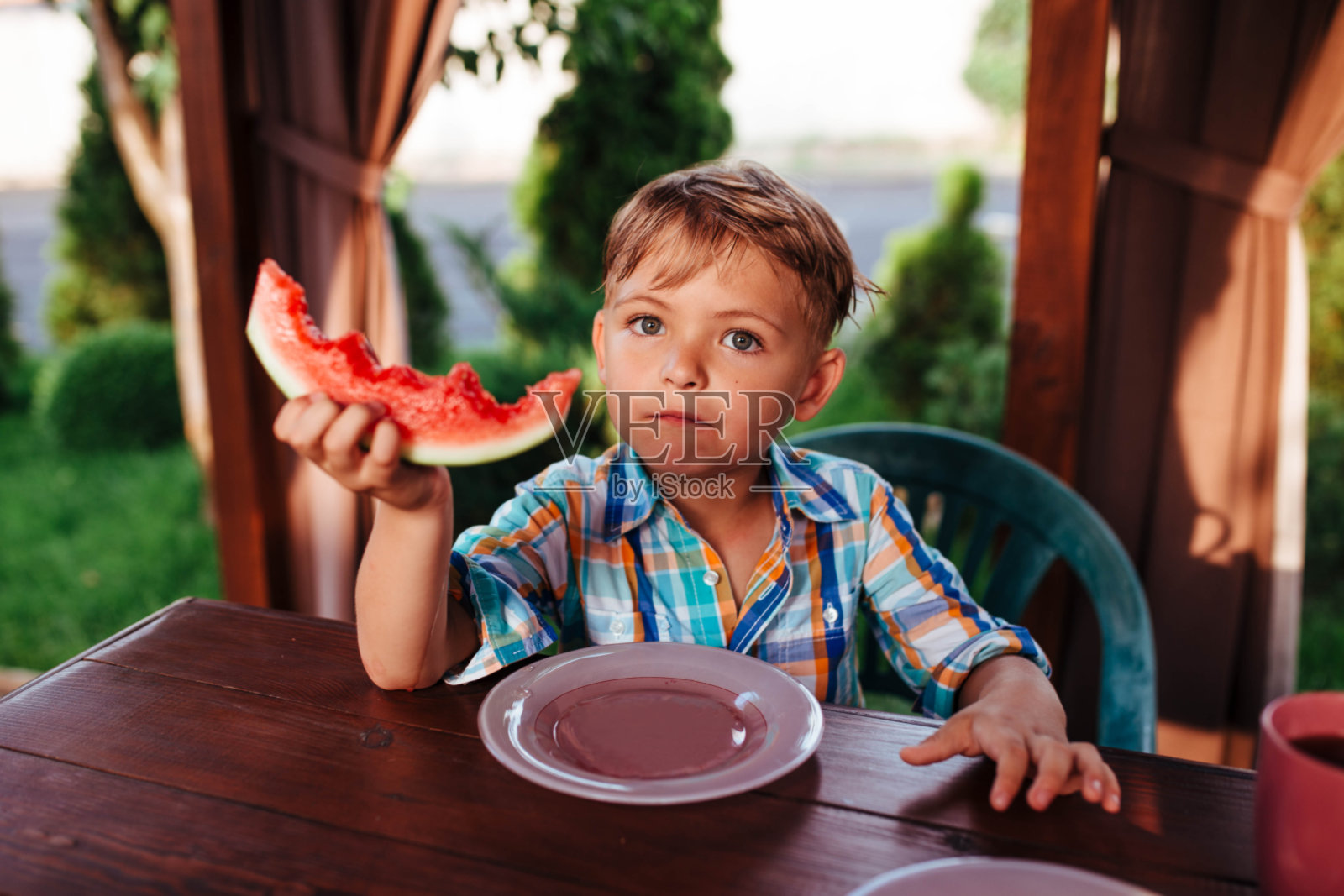 学前班的小男孩在村子外面吃西瓜照片摄影图片