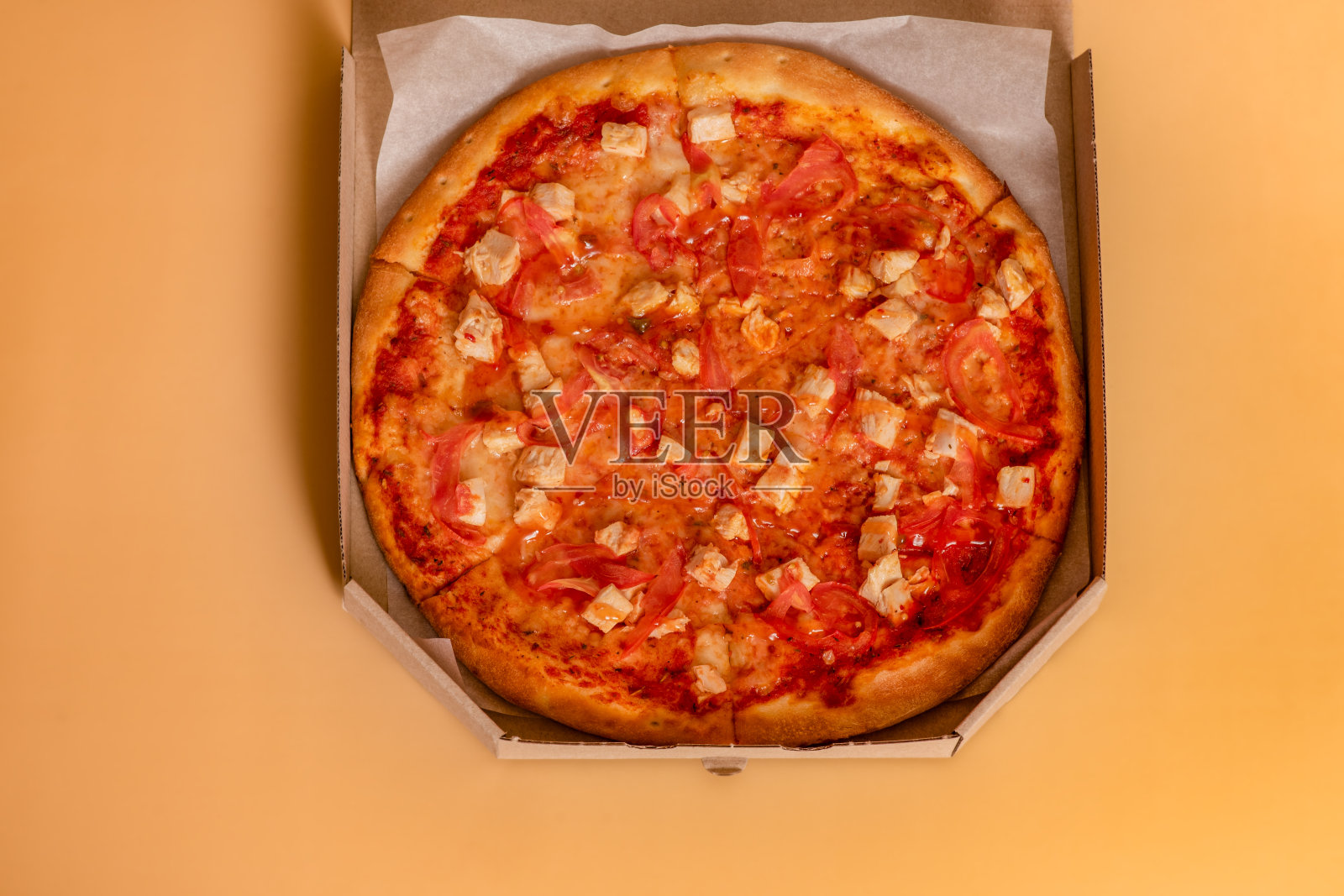 米色背景上的披萨。外卖食物。在厨房的桌子上有一个纸箱里的披萨。照片摄影图片