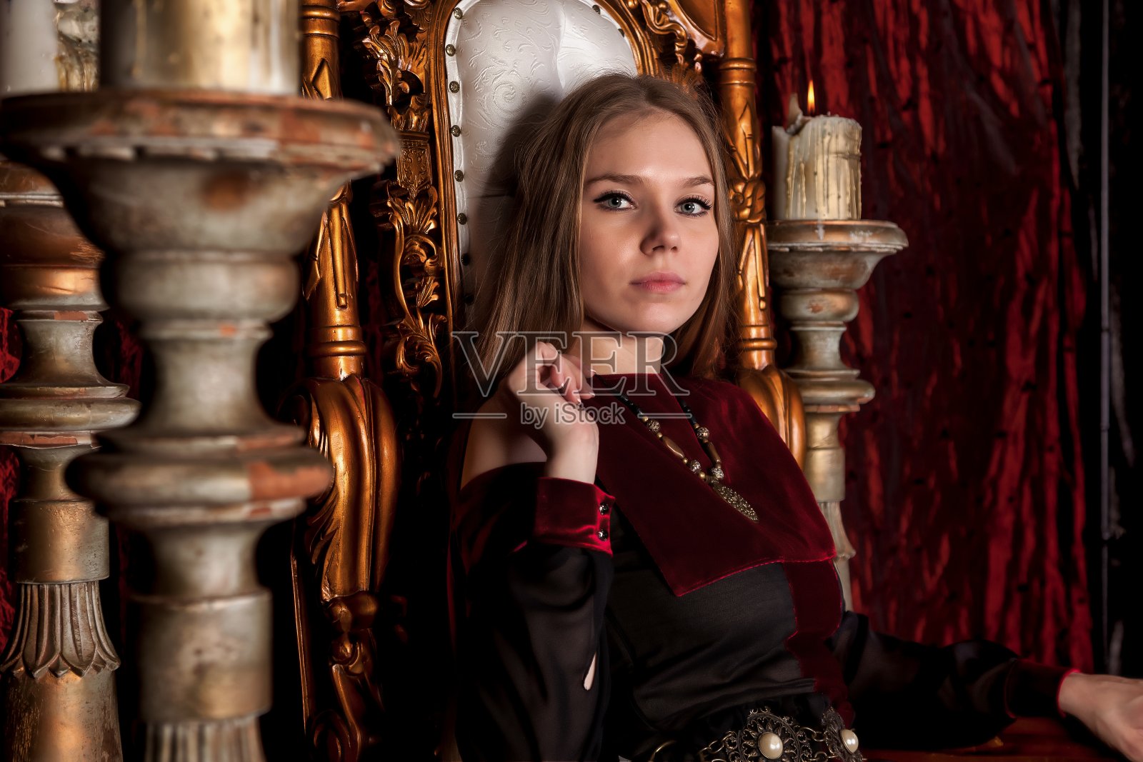 中世纪女王穿着历史服装，坐在城堡里的金色宝座上照片摄影图片