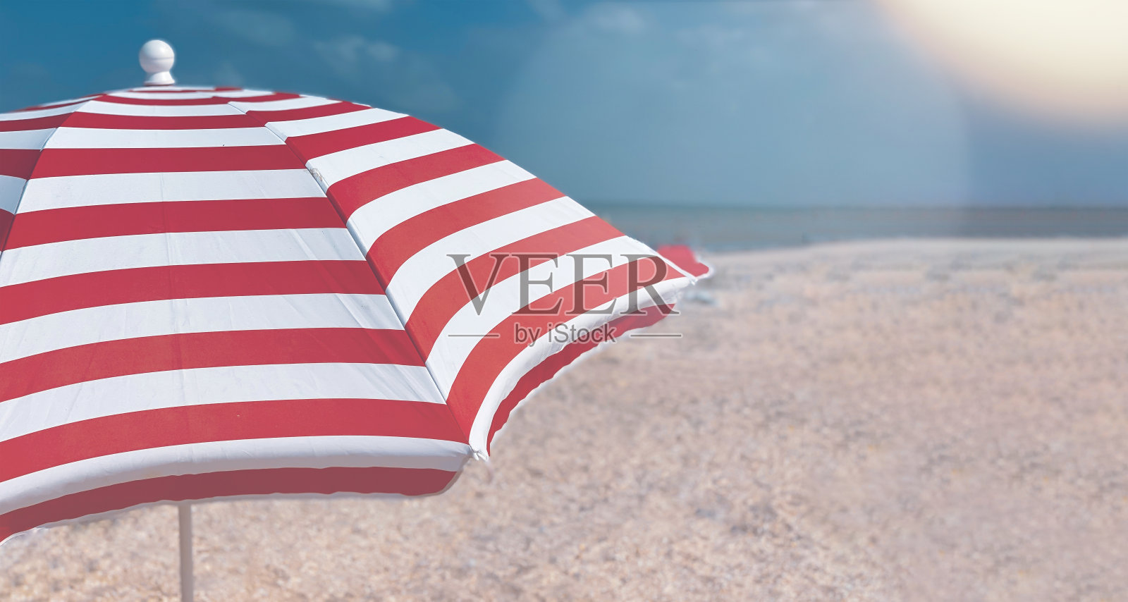 一部分的条纹沙滩伞映衬着美丽的蓝天，侧视图。照片摄影图片