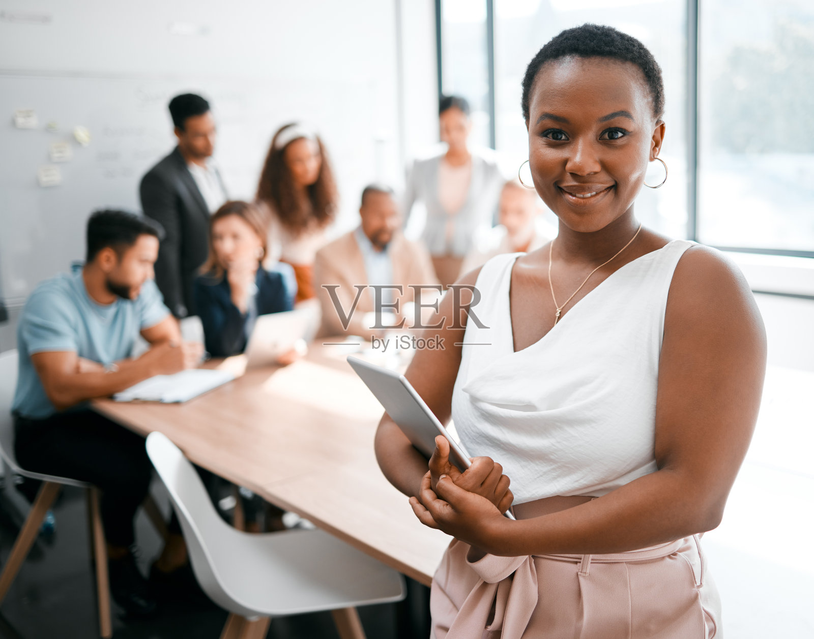 一位迷人的年轻女商人正在会议室开会，背景是她的同事照片摄影图片
