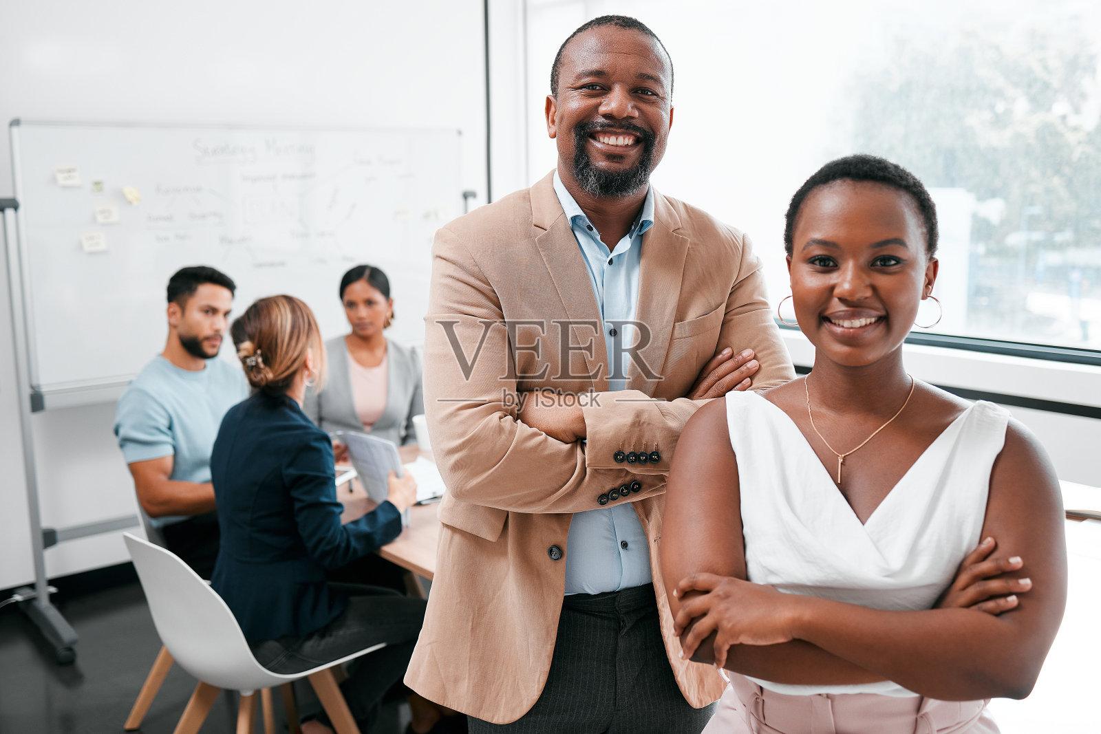 两名商界人士在会议室开会，背景是他们的同事照片摄影图片