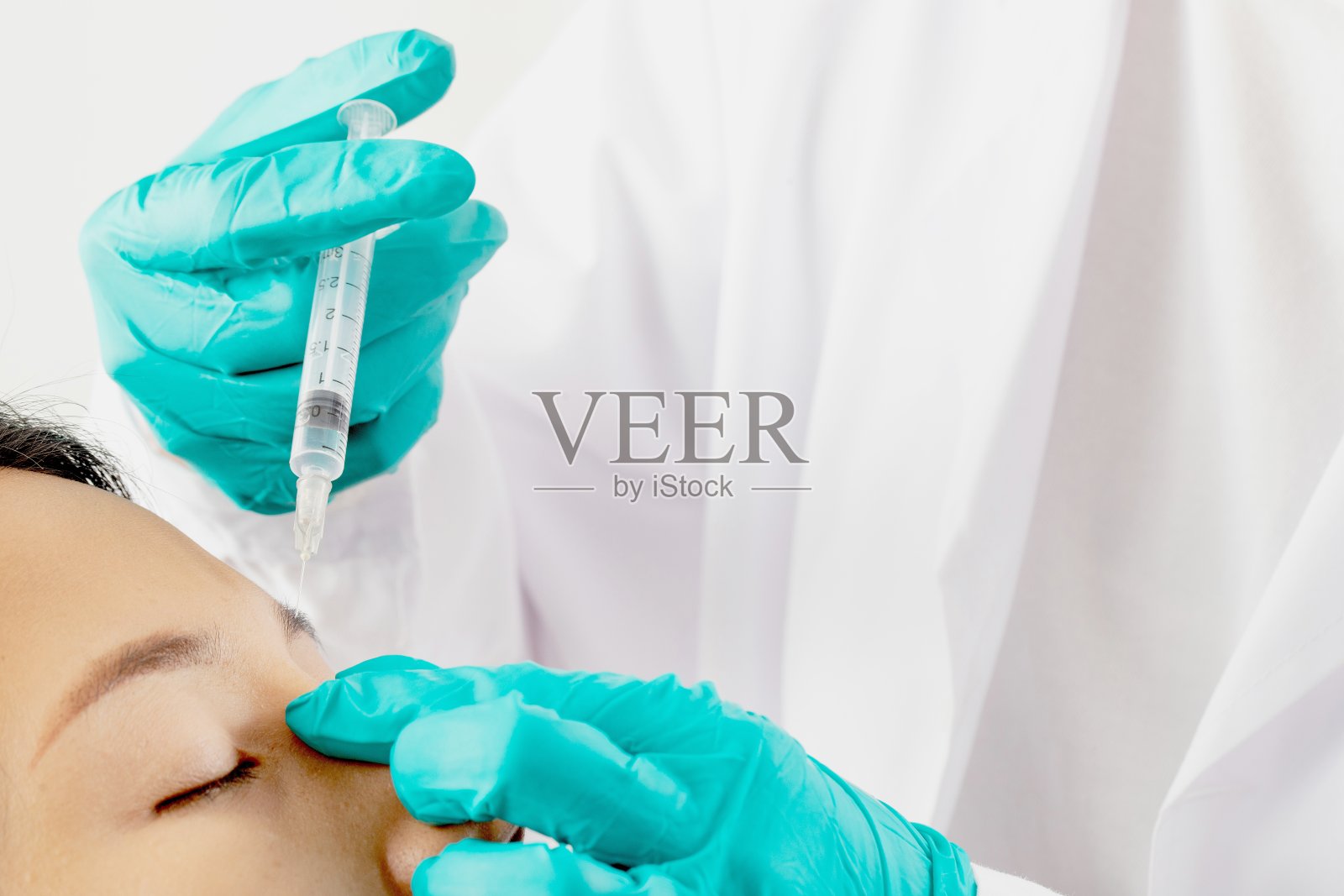 一个妇女注射填充物来提容。照片摄影图片