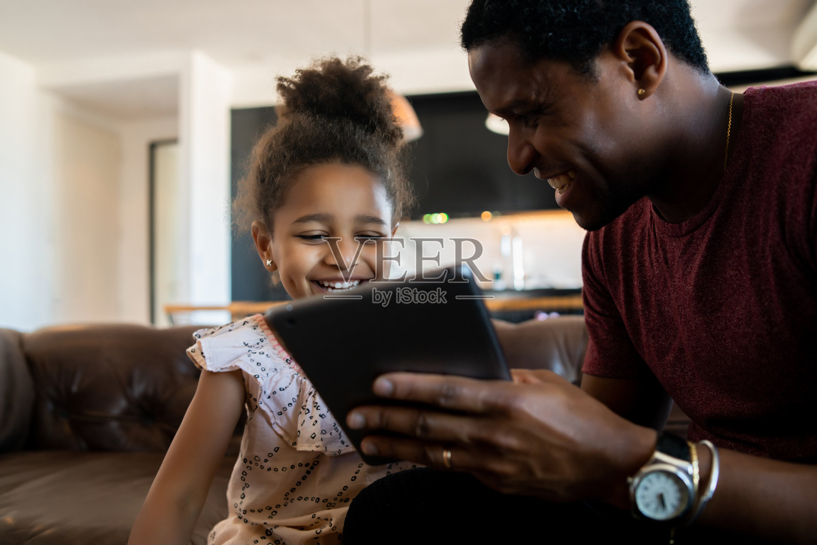 父亲和女儿在家里使用数码平板电脑。照片摄影图片