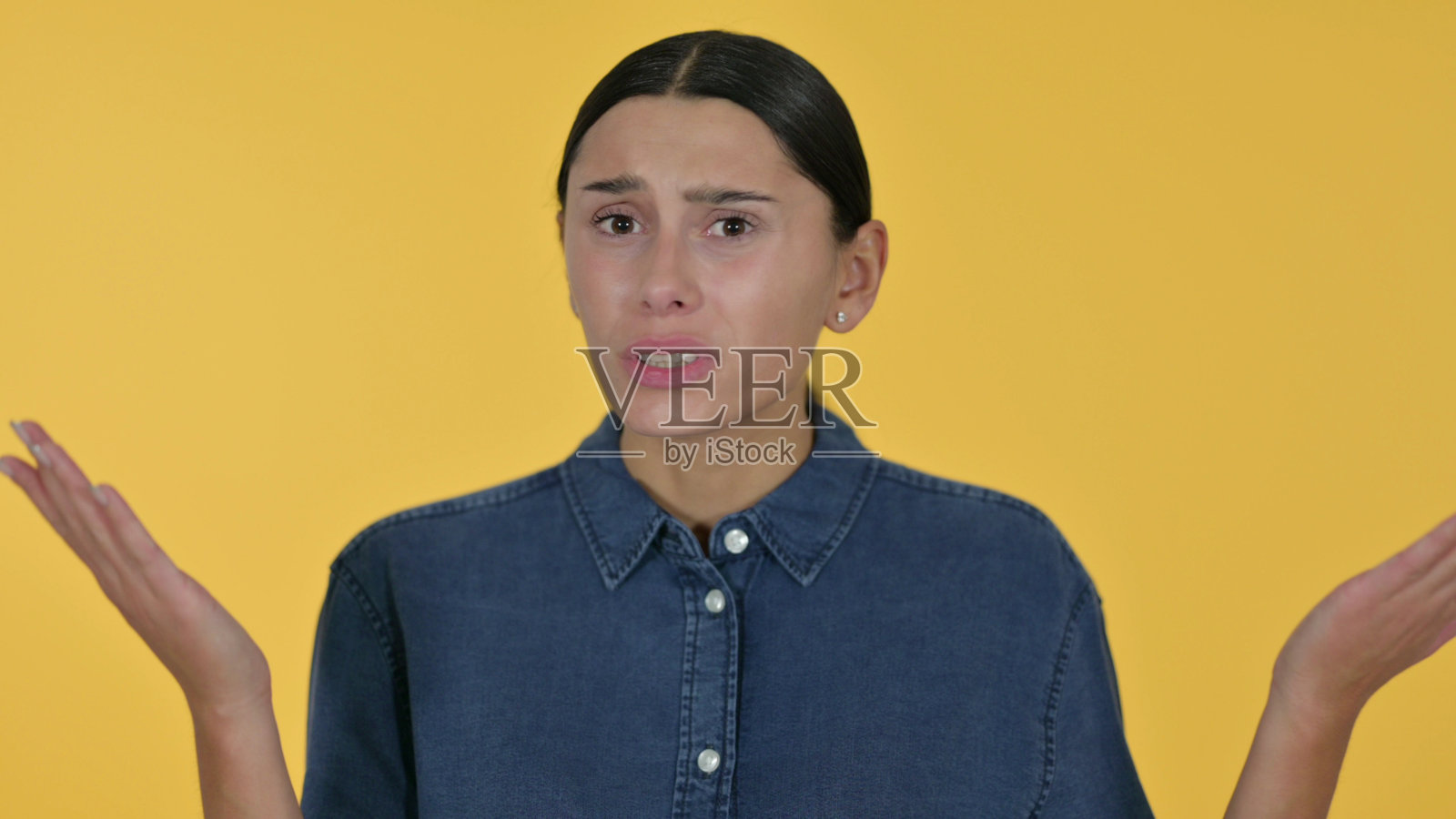失落的年轻拉丁女人，黄色背景照片摄影图片