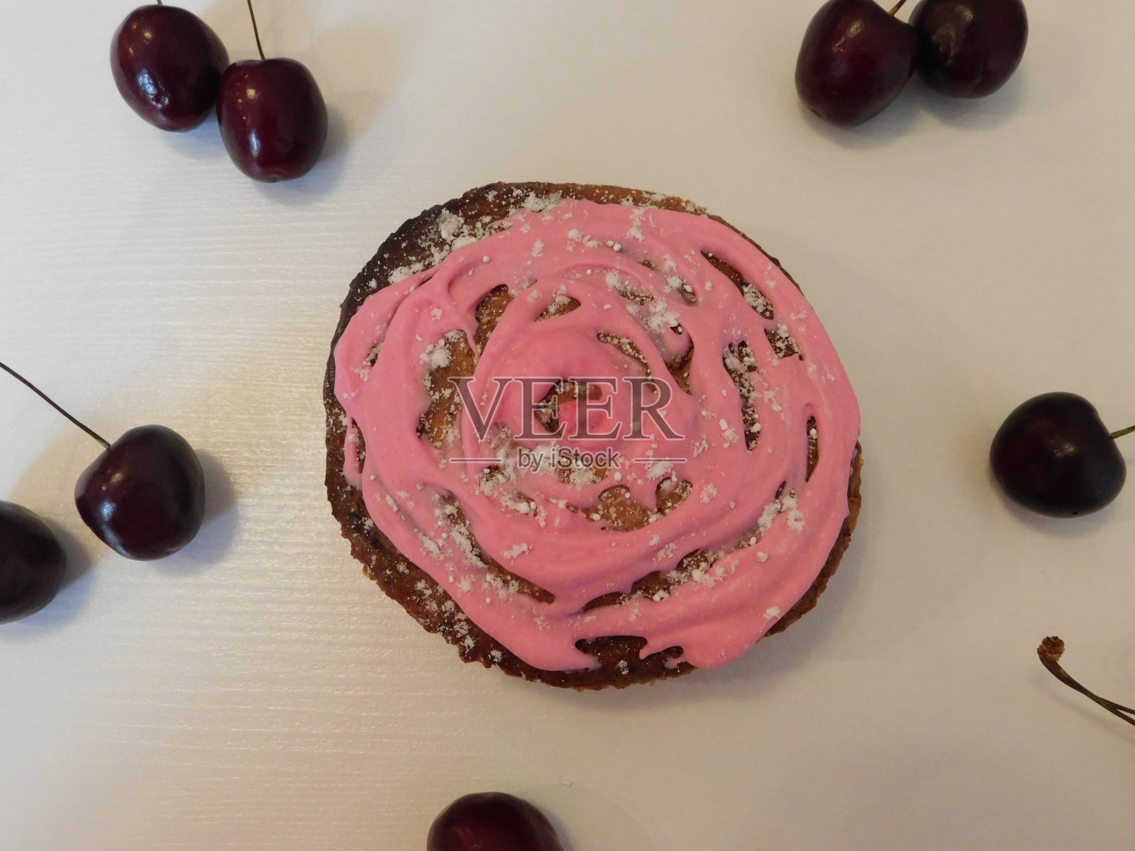 白桌子上放着自制的小蛋糕和新鲜樱桃。照片摄影图片