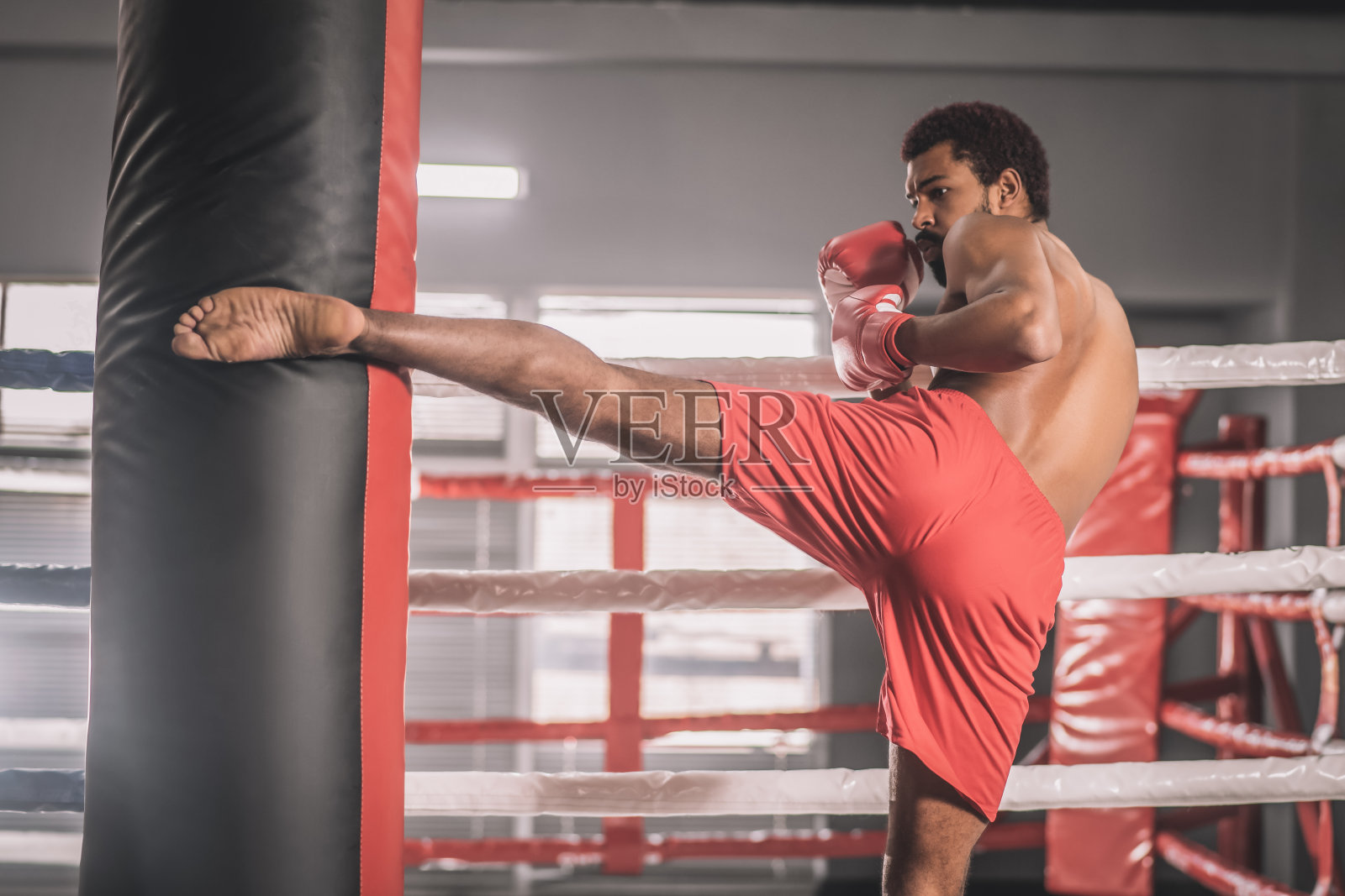 一个皮肤黝黑的自由搏击手用腿踢沙袋照片摄影图片