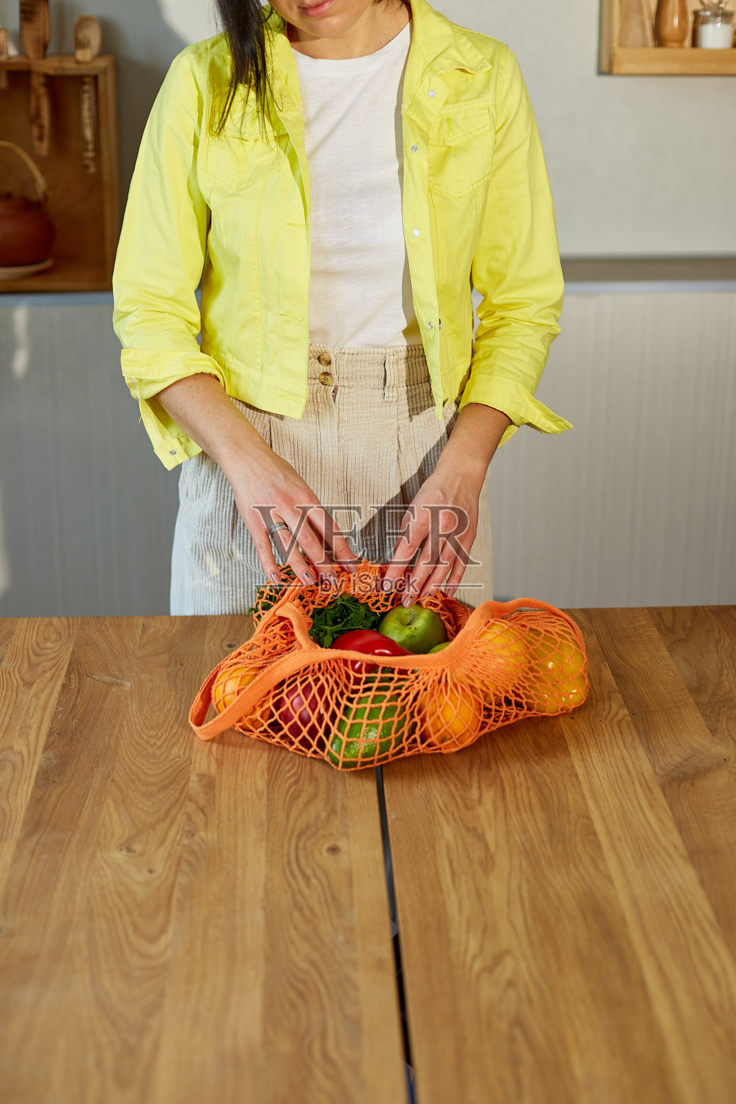 女人在黄色夹克拆包装购物网环保袋照片摄影图片