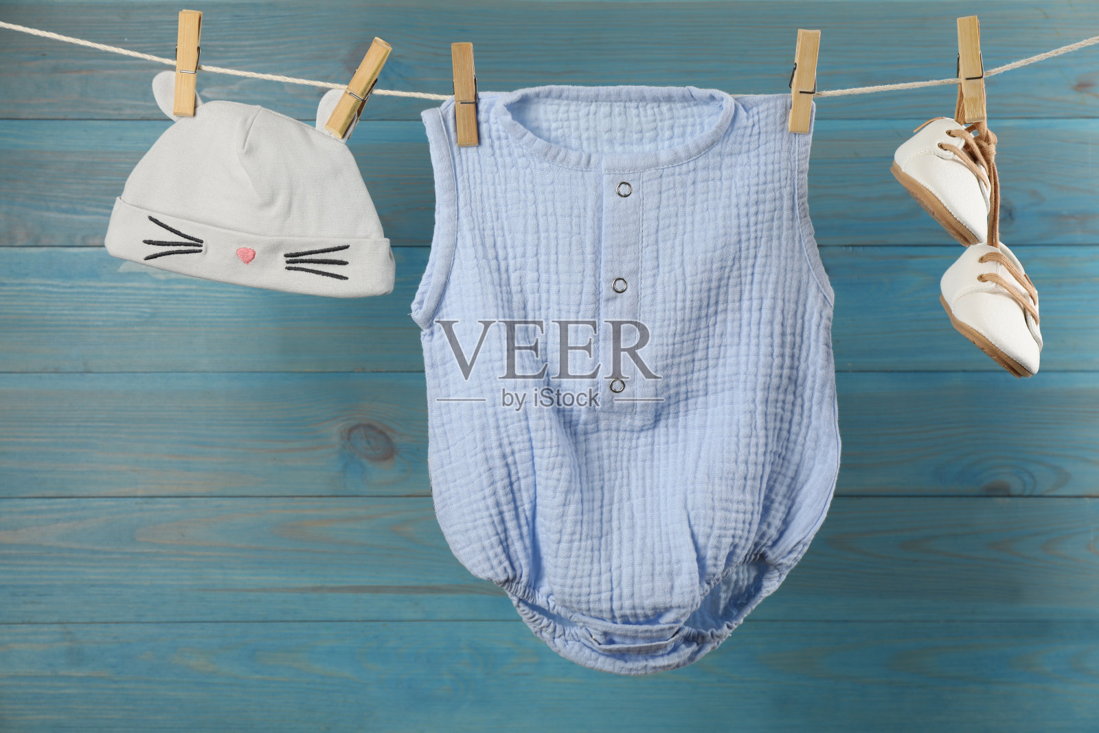 婴儿衣服挂在晾衣绳上，靠近浅蓝色的木墙照片摄影图片