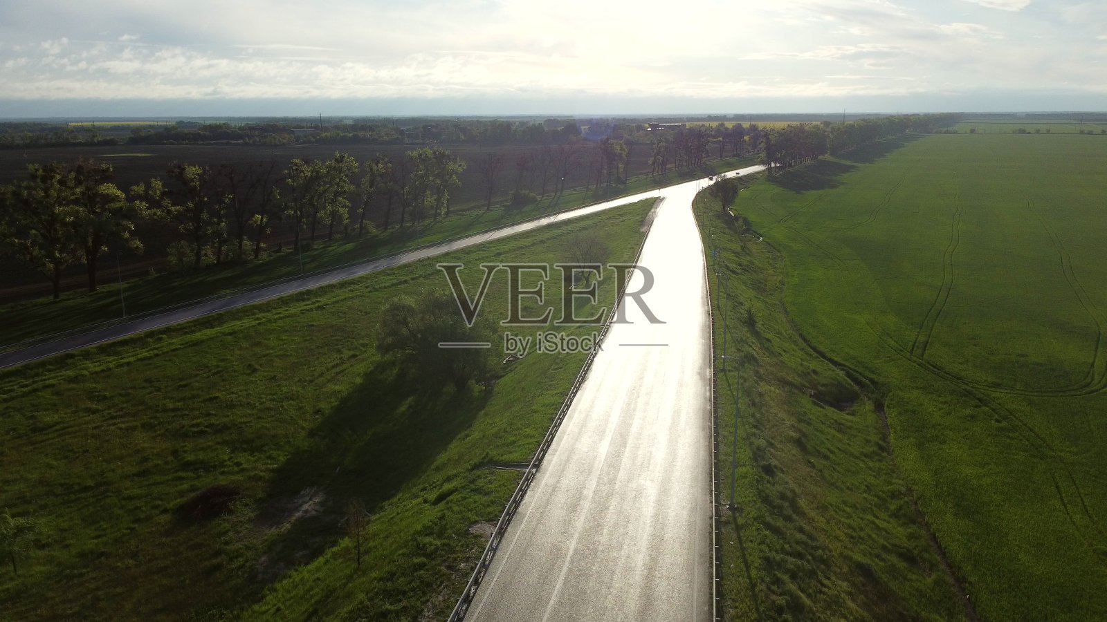 无人机降落在潮湿的柏油路上，让汽车在播种的土地之间穿行照片摄影图片