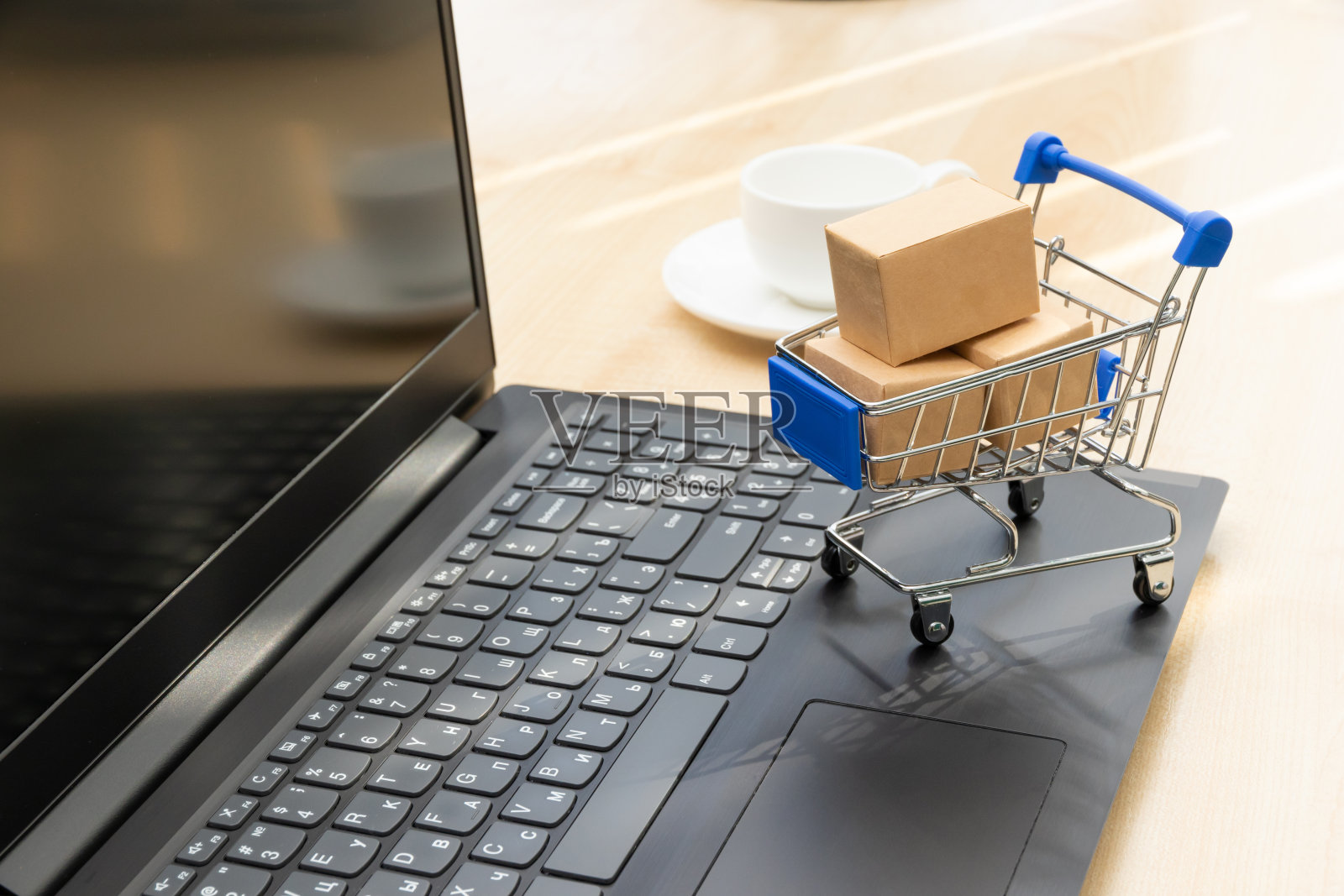 金属铬推车，盒子的背景是一个黑色的笔记本电脑和一个咖啡杯在工作的木桌上照片摄影图片