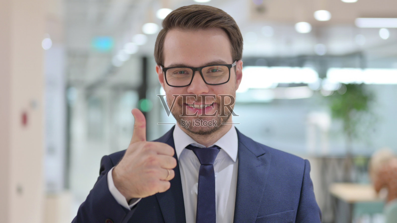 积极的年轻商人的肖像与拇指向上的手势照片摄影图片
