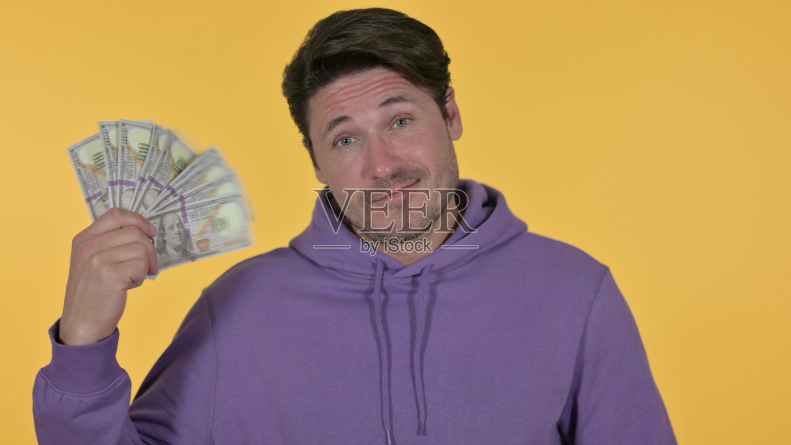 兴奋的中年男子持有美元，黄色背景照片摄影图片