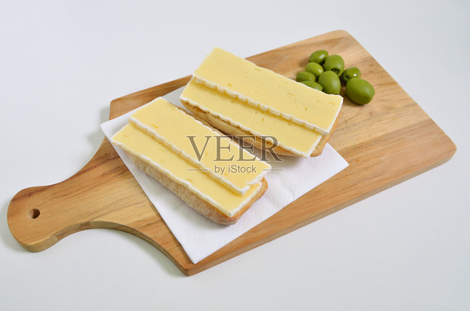 切菜板上的奶酪三明治和绿橄榄，特写，孤立在白色背景上照片摄影图片