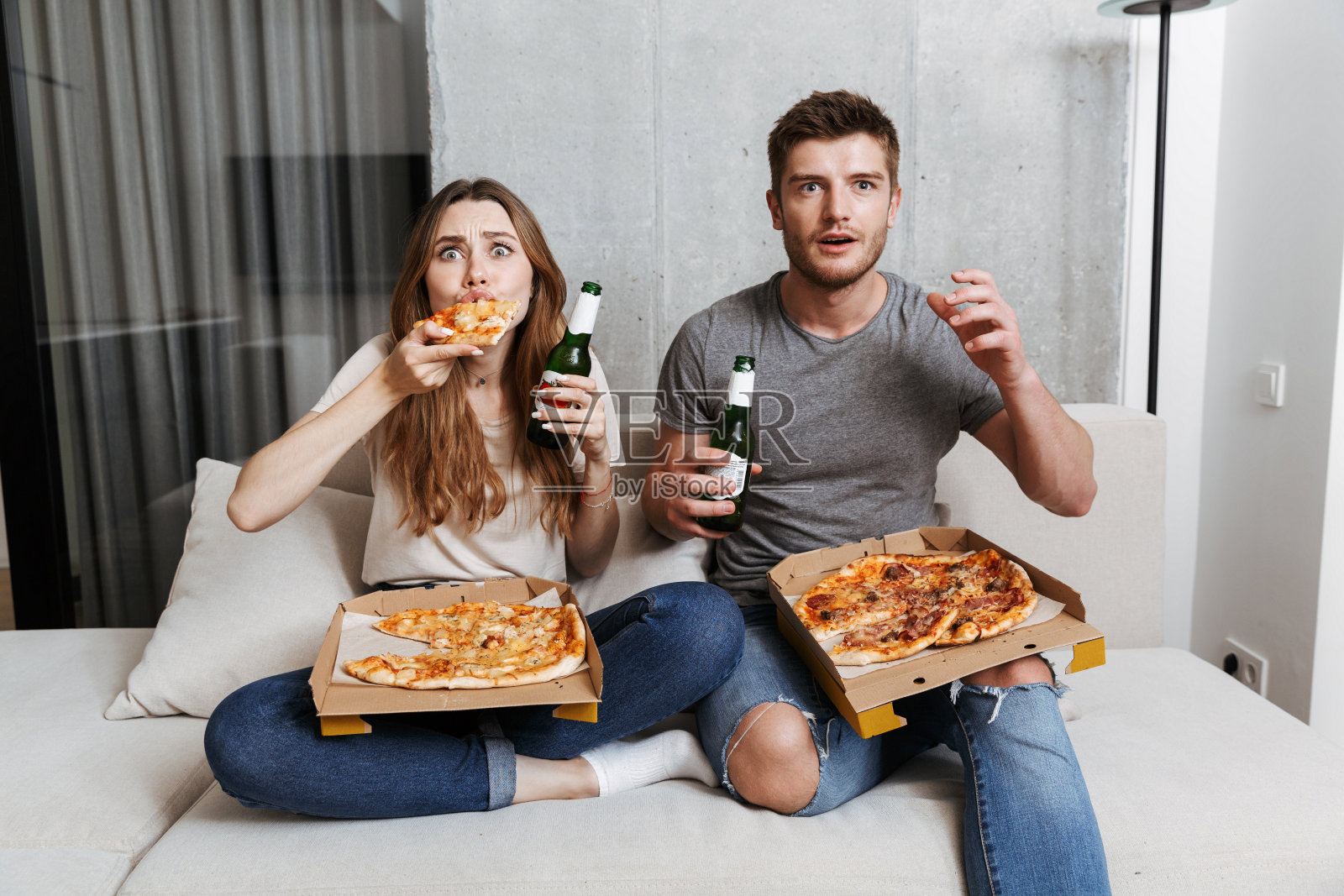 快乐的年轻夫妇吃着披萨，喝着啤酒照片摄影图片