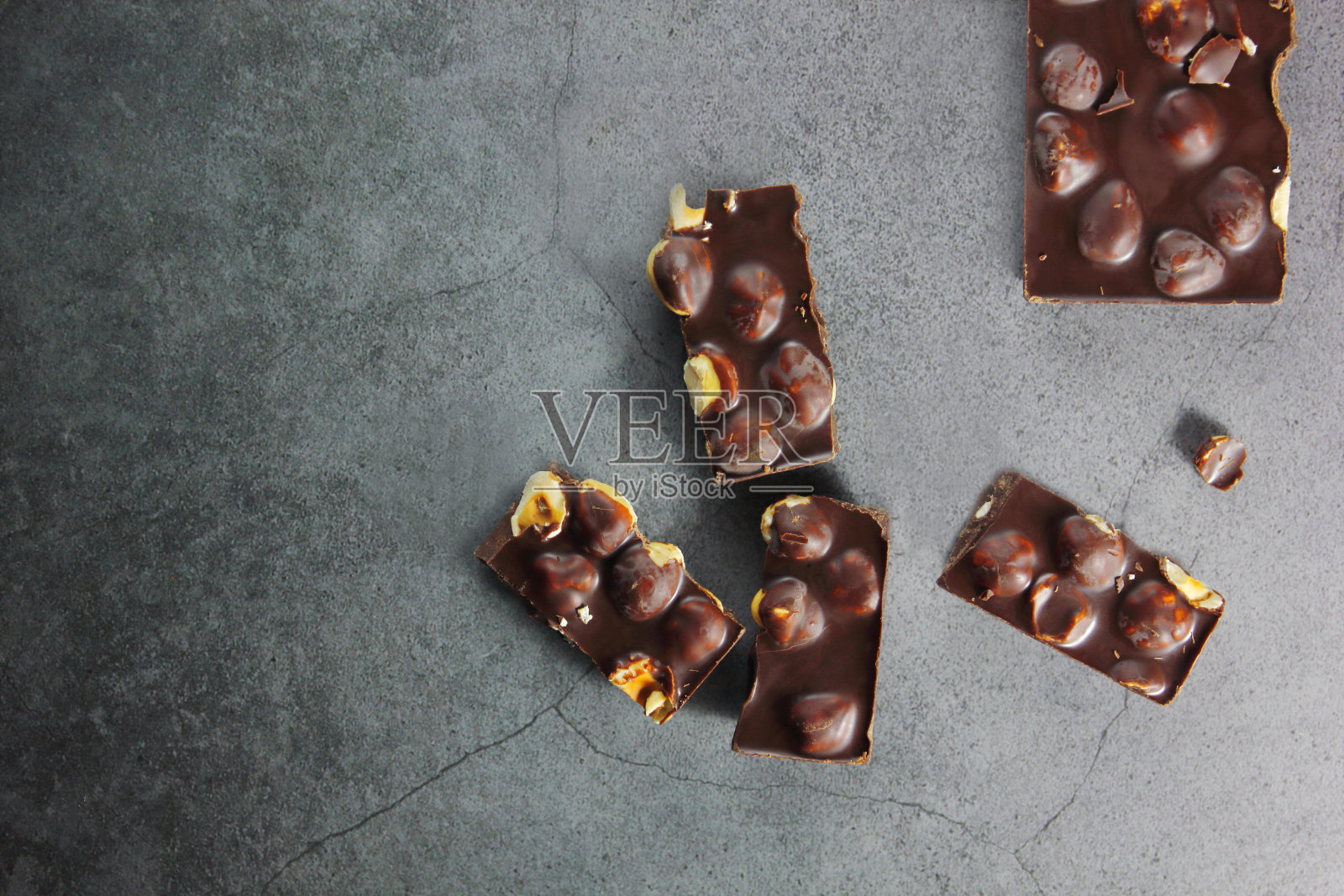 巧克力碎片和榛子在灰色的背景与空间复制，平层。巧克力棒。巧克力的背景。配方。副本的空间。照片摄影图片