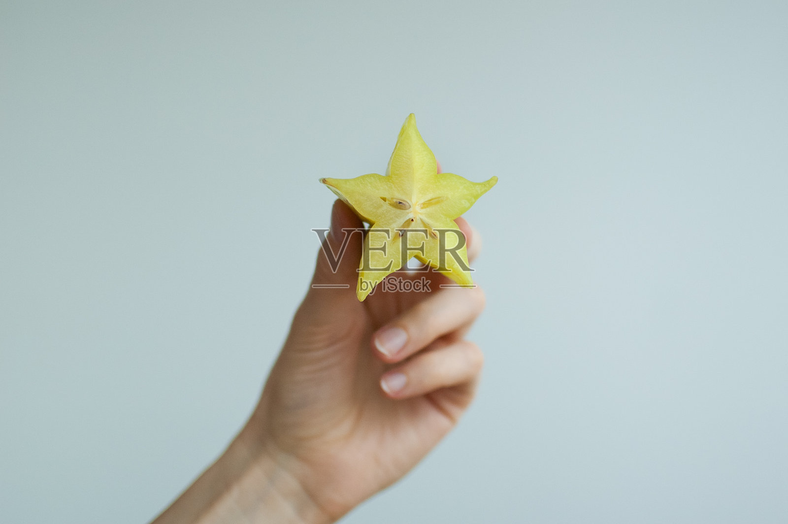 女性手里拿着一片异国的成熟杨桃或杨桃。健康食品，新鲜有机红星苹果水果照片摄影图片