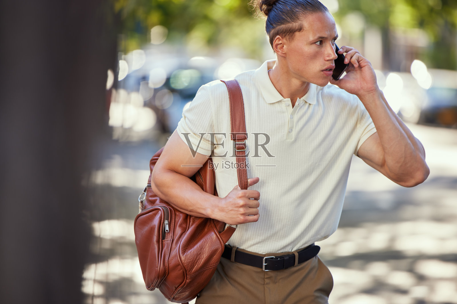 这是一个年轻人在城市里走路时打电话的照片照片摄影图片