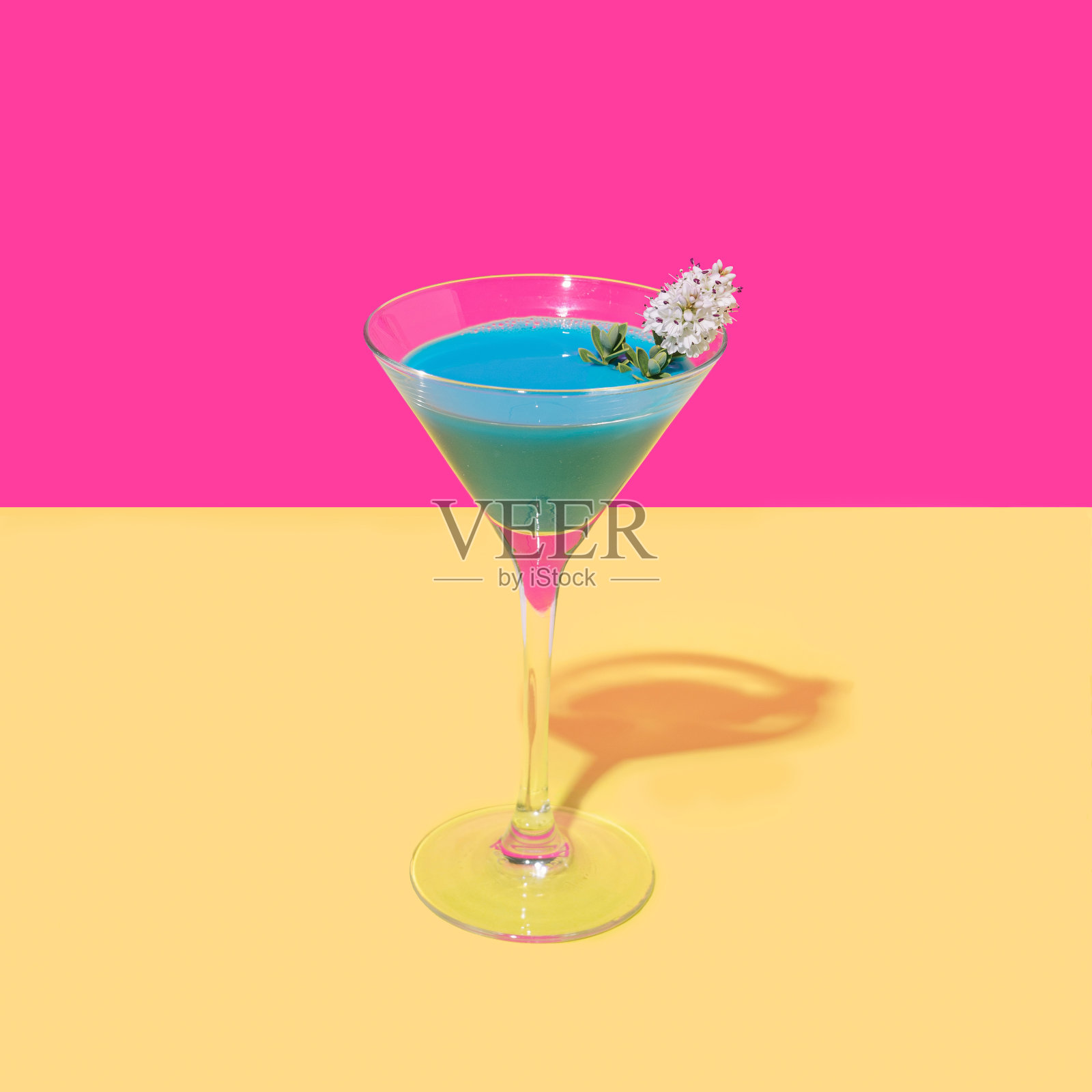 充满活力的蓝色鸡尾酒，白色的花，明亮的洋红色背景和温暖的黄色底。乐观的概念。照片摄影图片