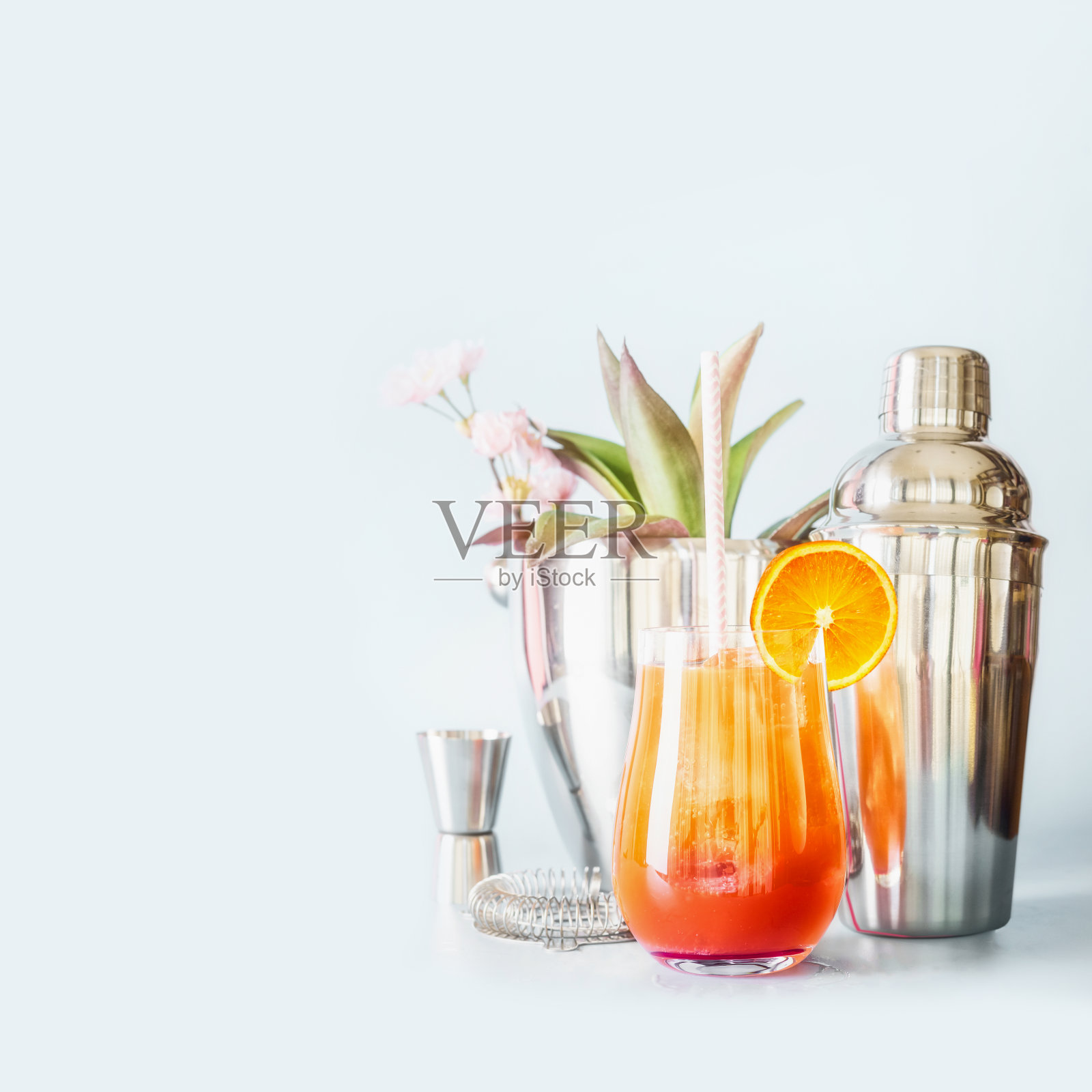 黄橙长饮配冰块，橙片和饮用吸管在玻璃杯中与鸡尾酒吧工具照片摄影图片