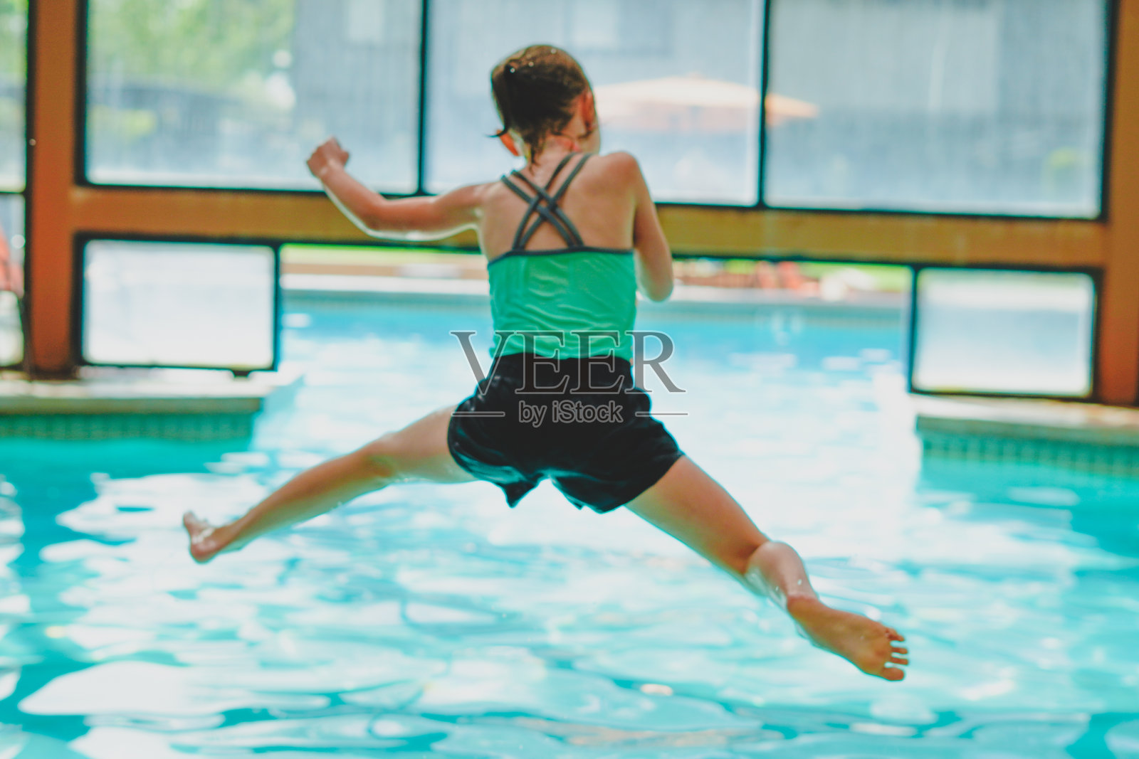 小女孩在游泳池里蹦蹦跳跳照片摄影图片