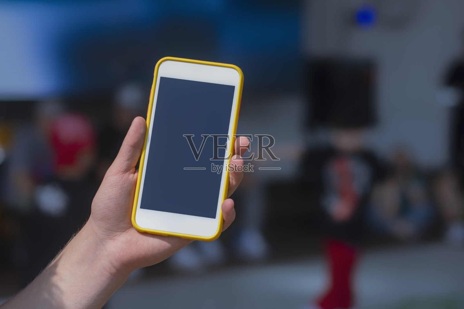 在儿童舞蹈锦标赛的背景下，他手里拿着一个智能手机的模型。照片摄影图片