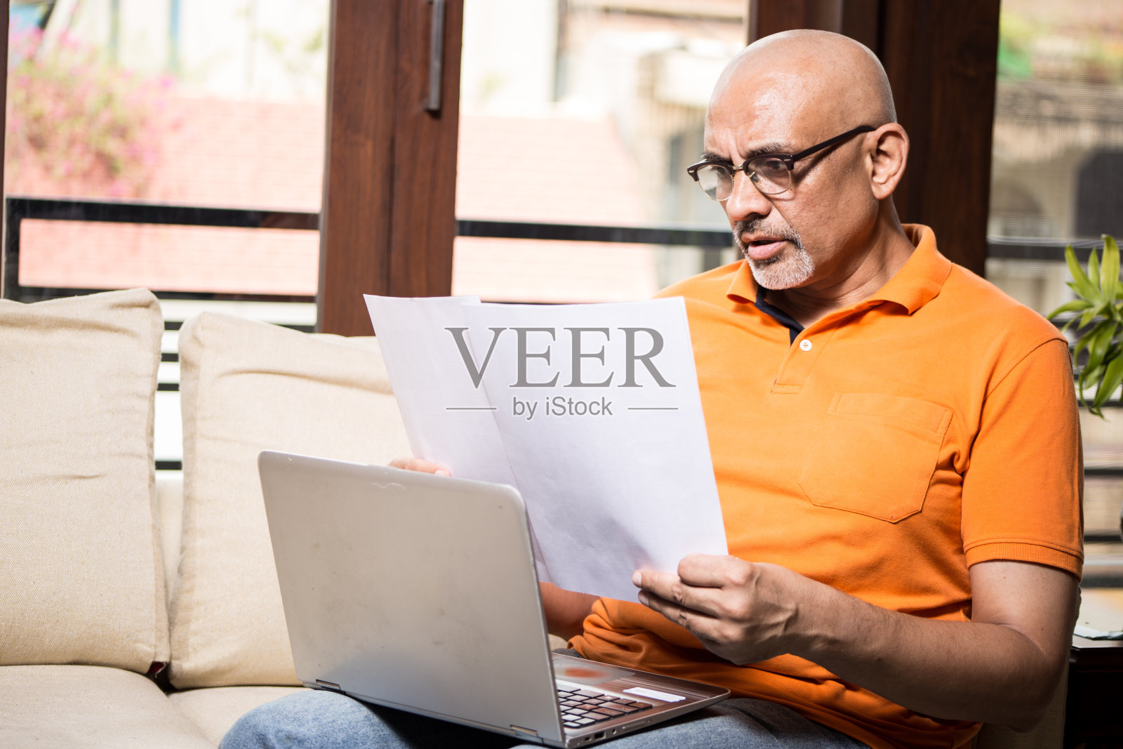 穿着休闲装的中年男子在家里用笔记本电脑看文件照片摄影图片