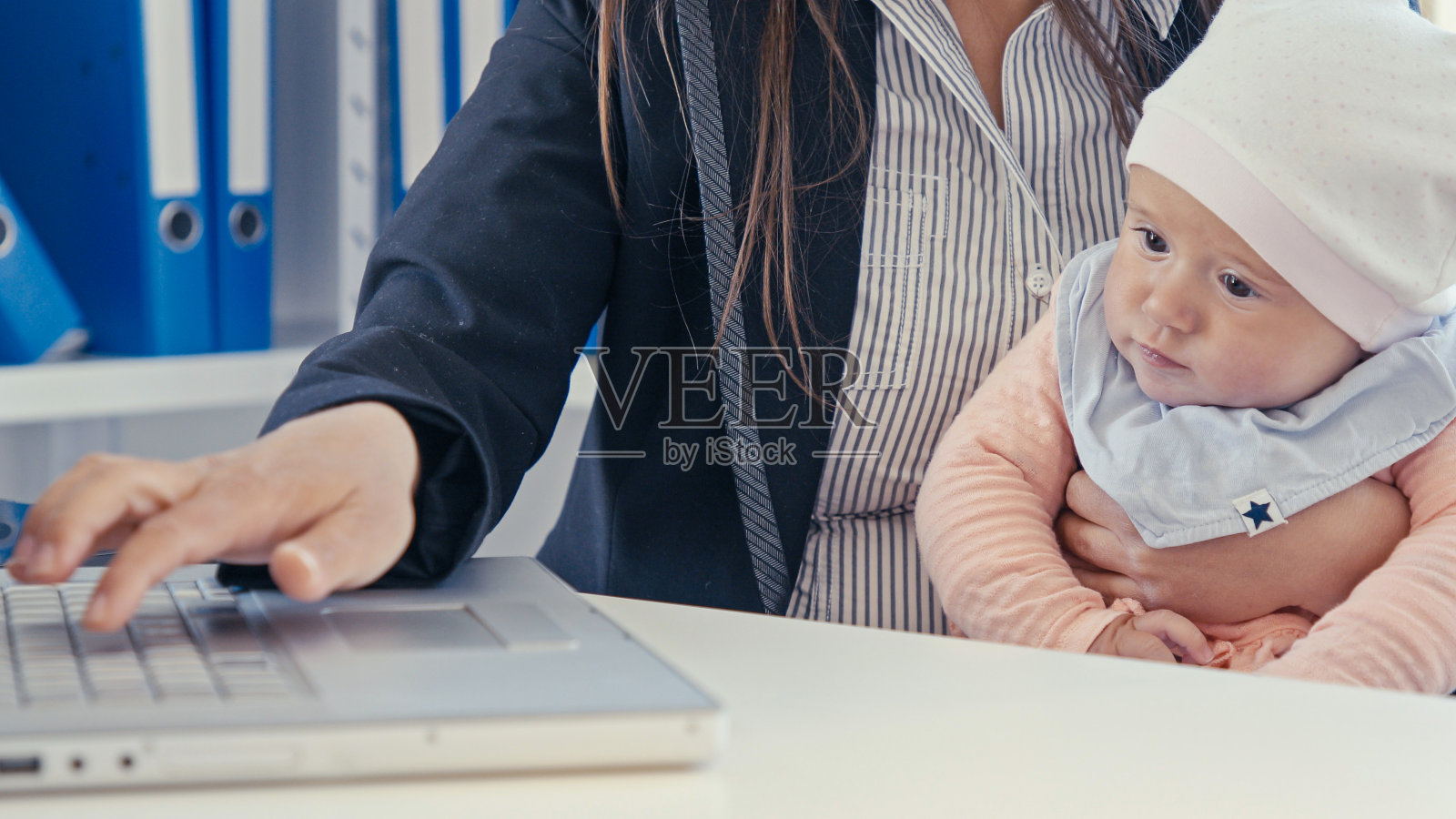 带着孩子在办公室用笔记本电脑工作的女商人，COVID-19大流行。关闭了。照片摄影图片