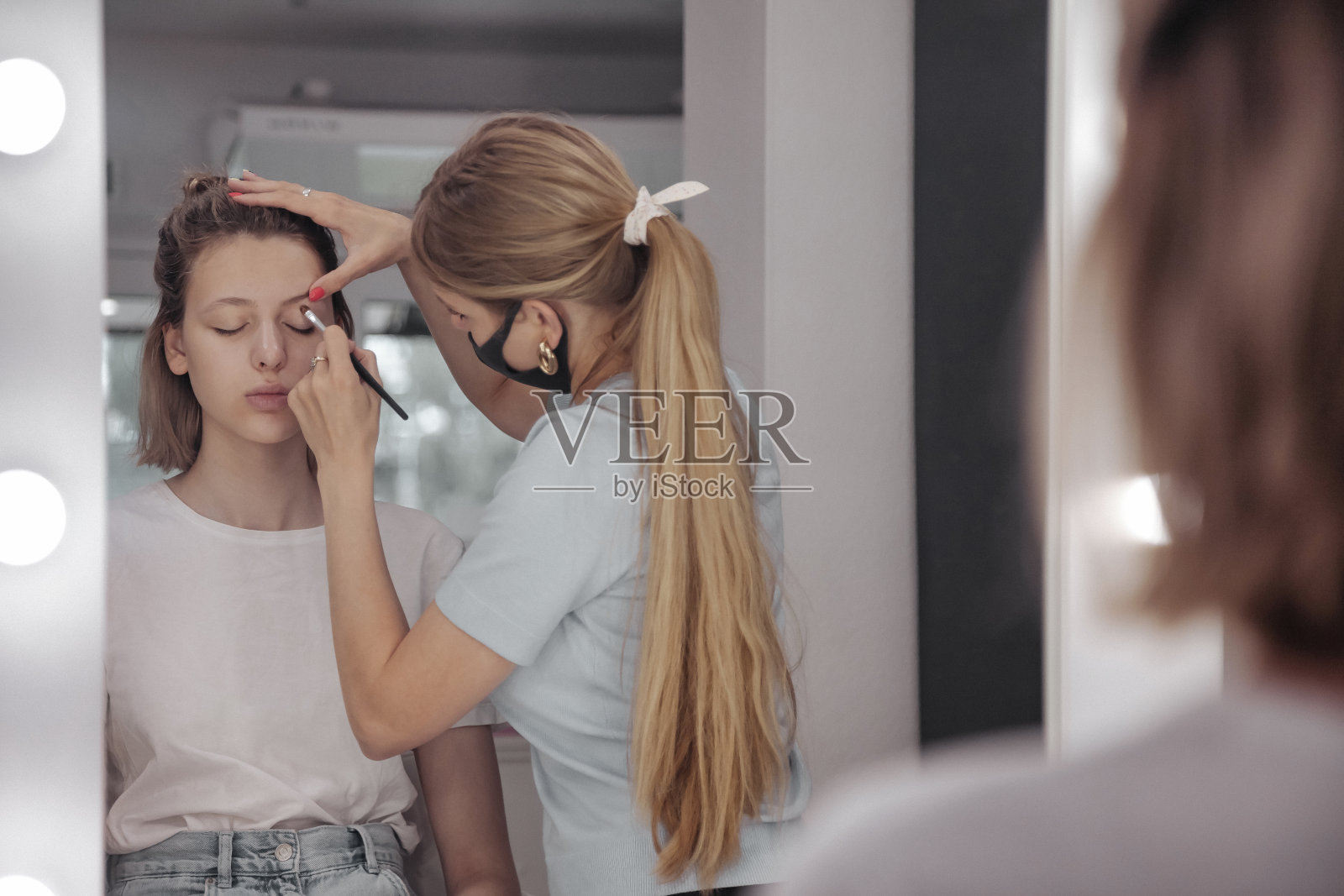 女化妆师在美容院为可爱的年轻女子化妆照片摄影图片