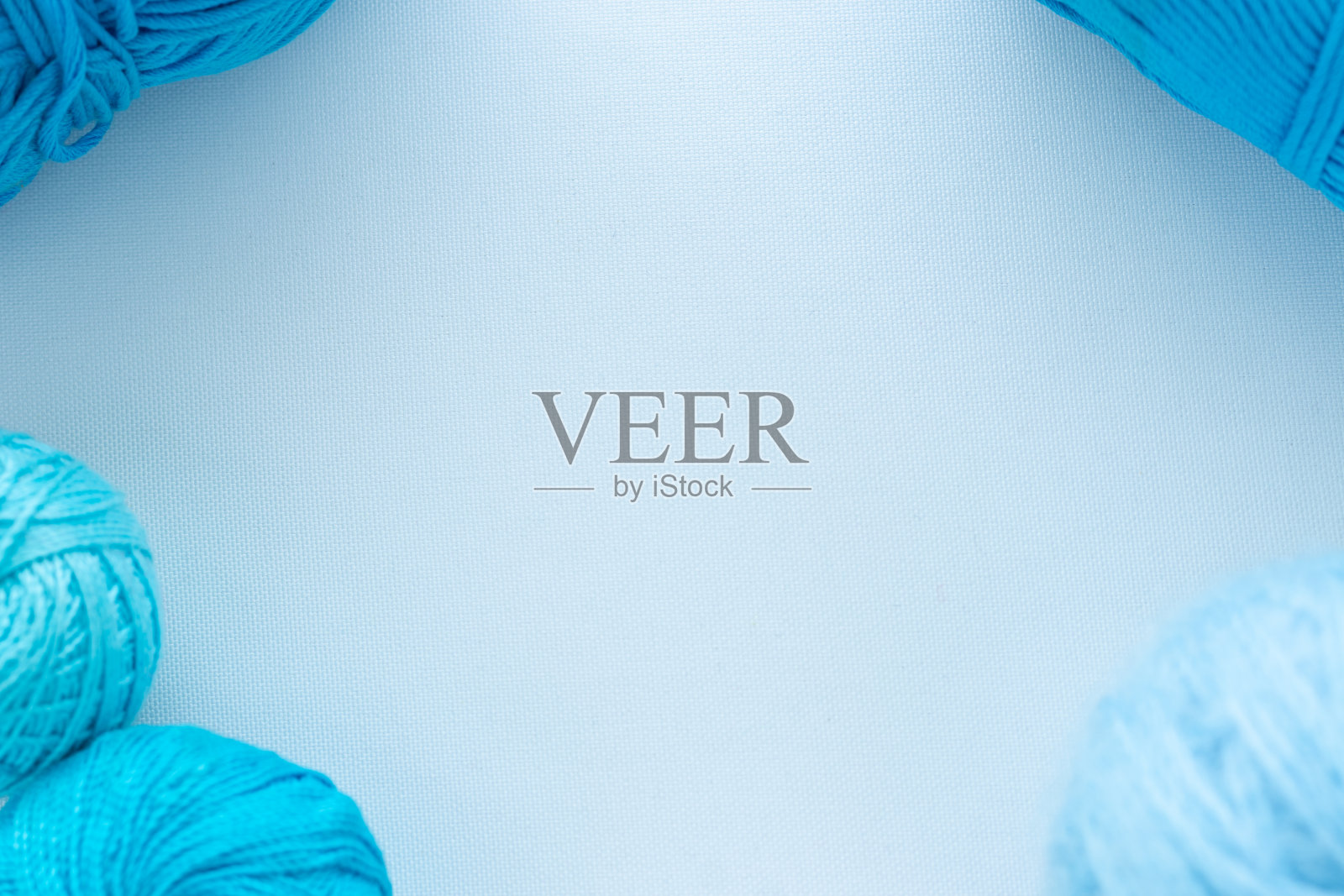 框架的边缘和角落由蓝色的线和球编织，手工和爱好在白色背景从织物复制空间照片摄影图片