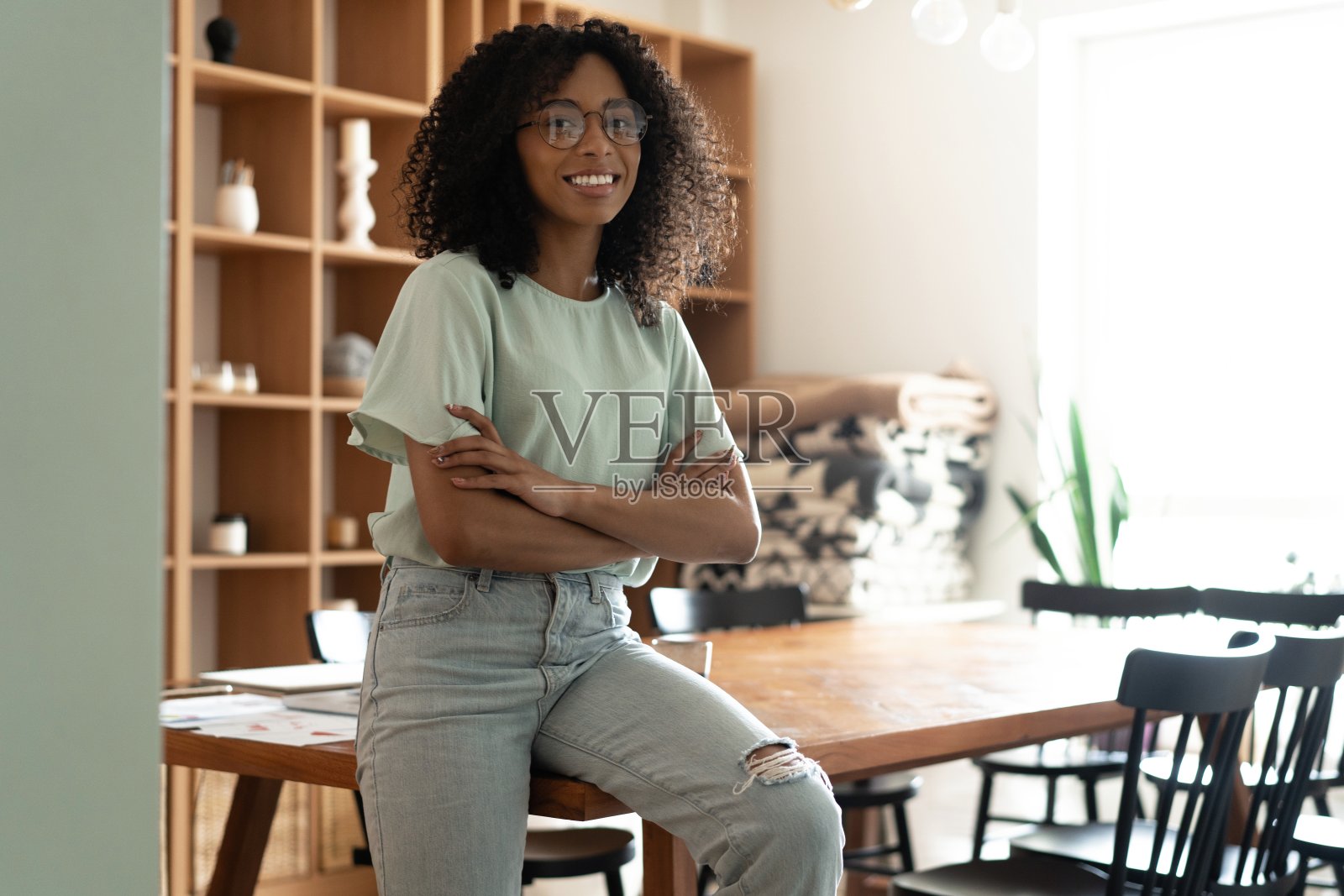 在她的办公室里，一个快乐，微笑的混血女商人的肖像。照片摄影图片