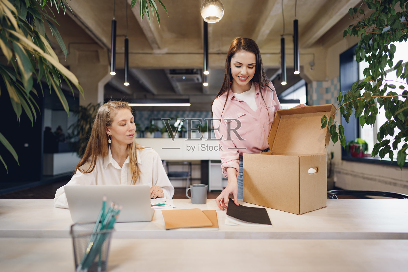 年轻的女商人在辞去工作后，拿着一箱私人物品准备离开办公室照片摄影图片